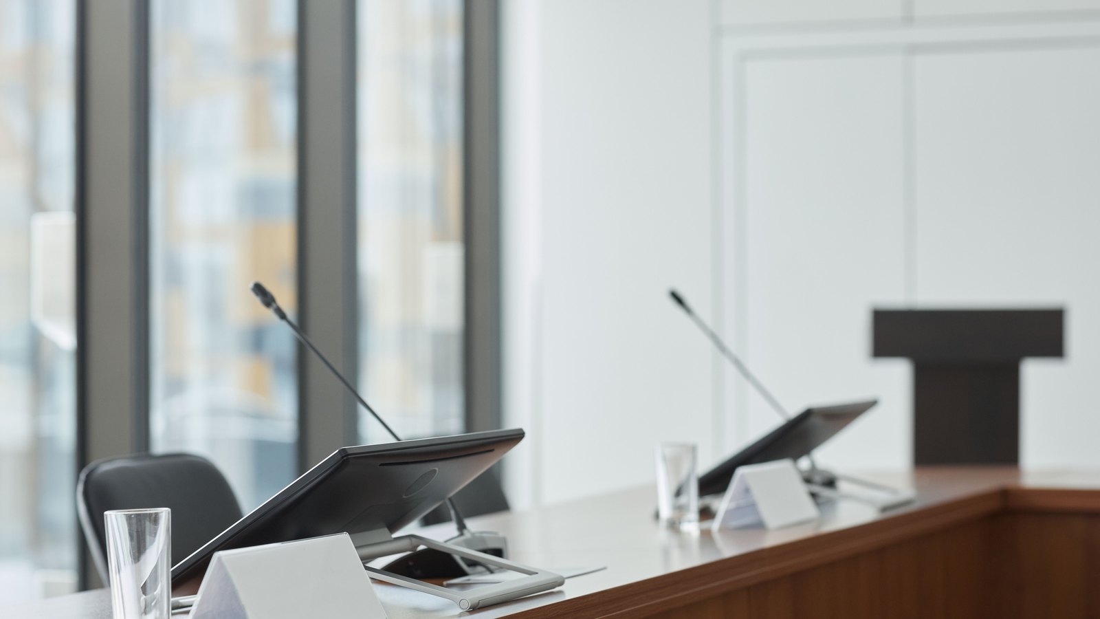 An empty meeting desk with microphones and blank display panels, not a photograph of this event.