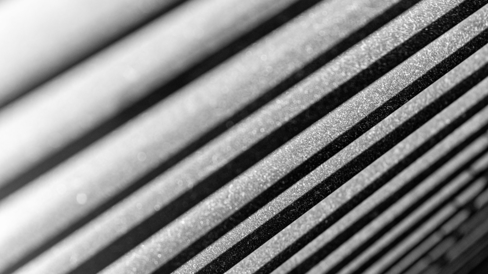 A monochrome macro of a ribbed surface running diagonally across the frame, alternating pale raised ridges and deep black grooves, sharp at the right and falling out of focus toward the upper left. No text, brand mark, person or place is in view.