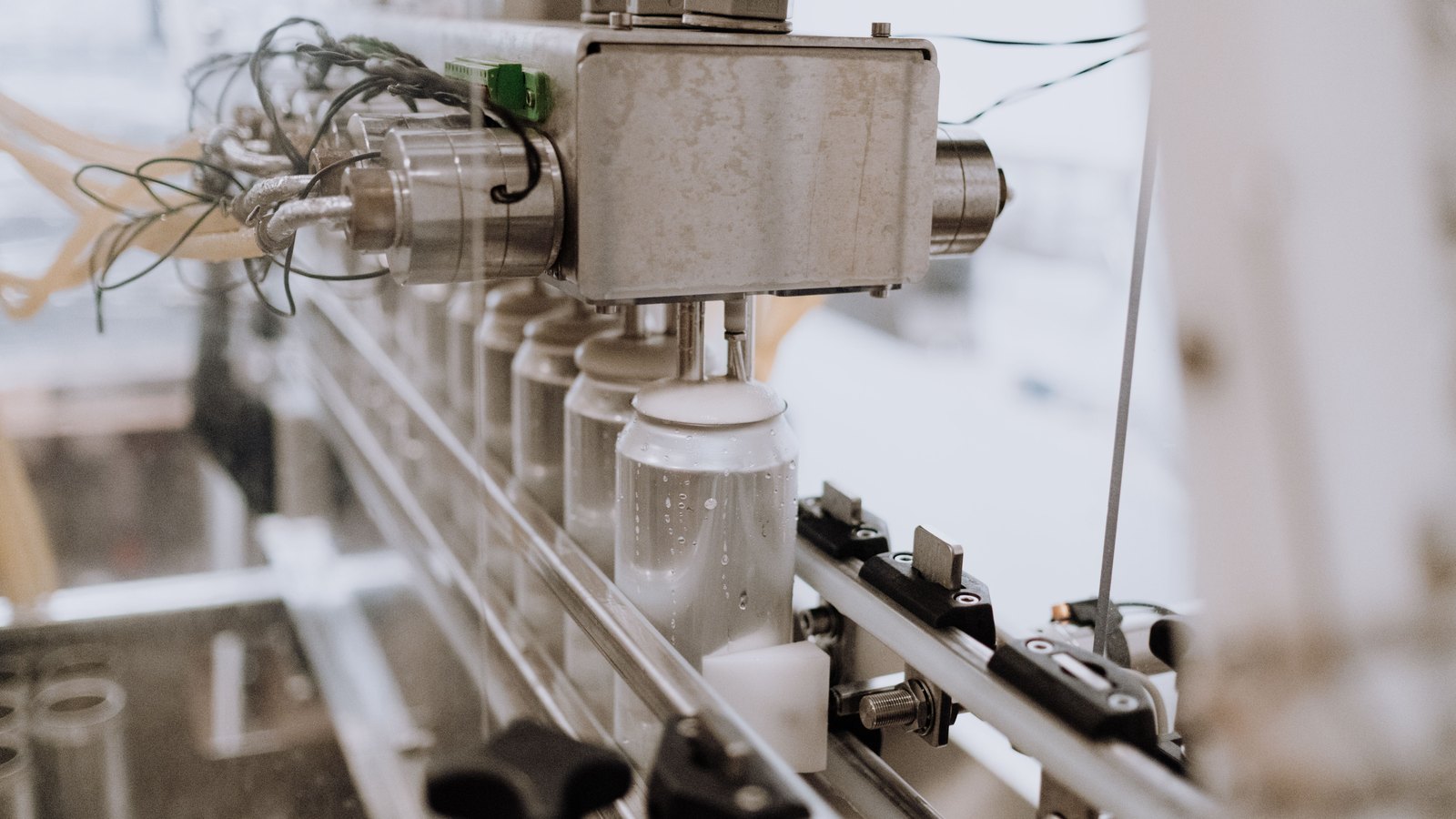 Automated machinery fills unbranded aluminum cans on a production line.