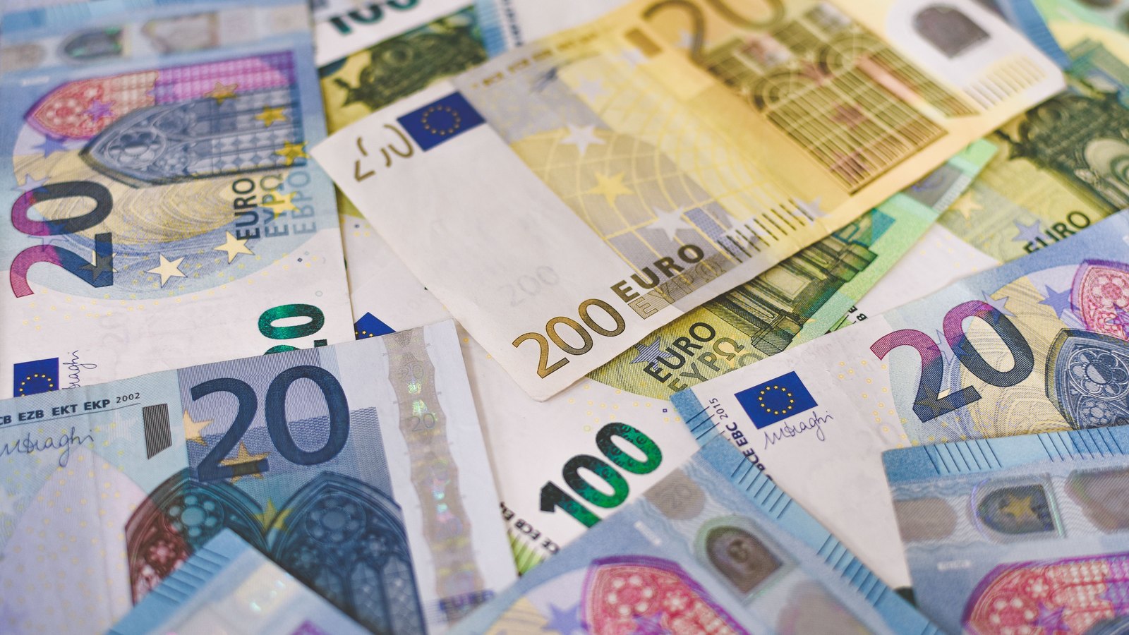 Twenty, one hundred and two hundred euro banknotes overlap in a close view.