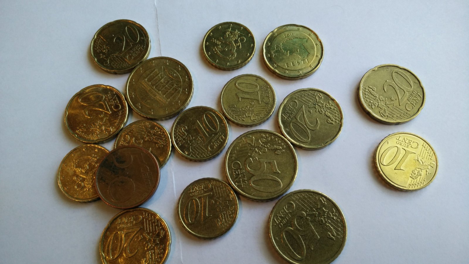 Euro coins of several denominations lie on a white surface.