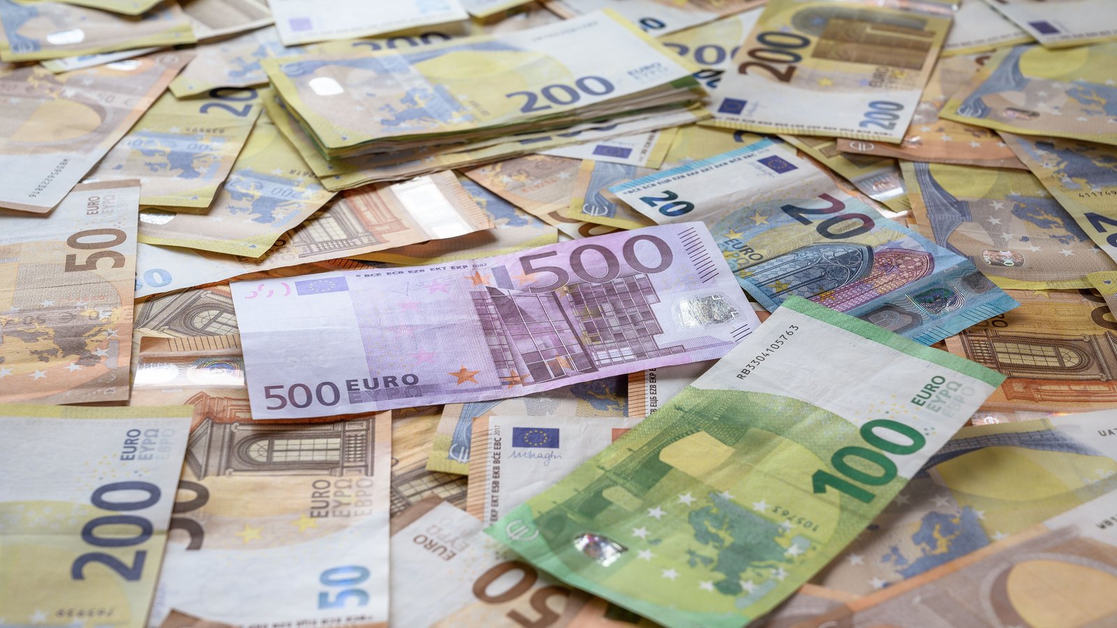 Euro banknotes in several denominations spread across a table