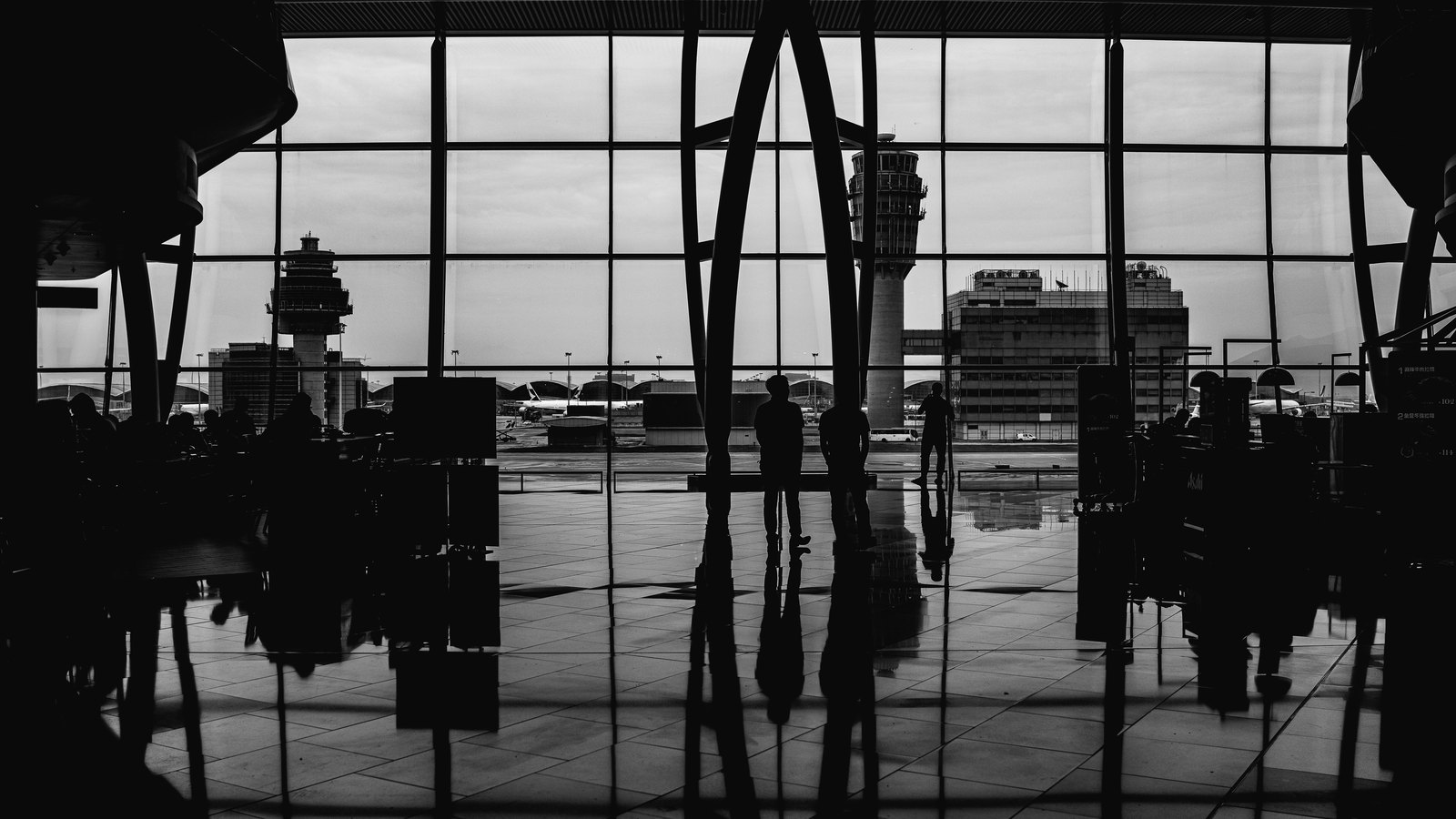 Silhouetted travelers wait inside an airport terminal in a stock photograph.