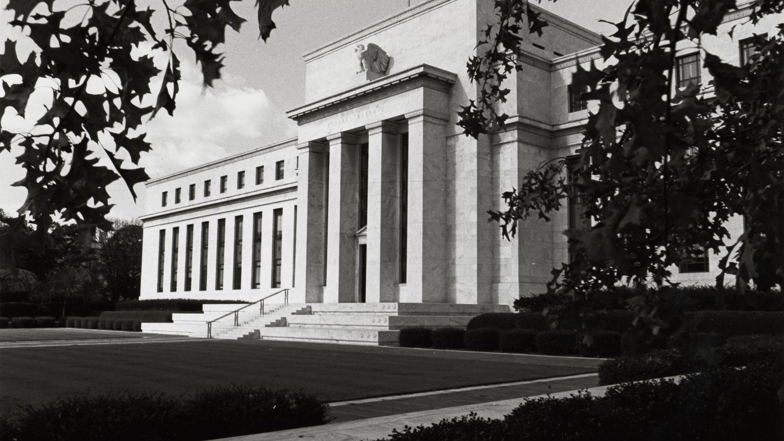An archival view of the Federal Reserve Board's Eccles Building in Washington framed by oak leaves.