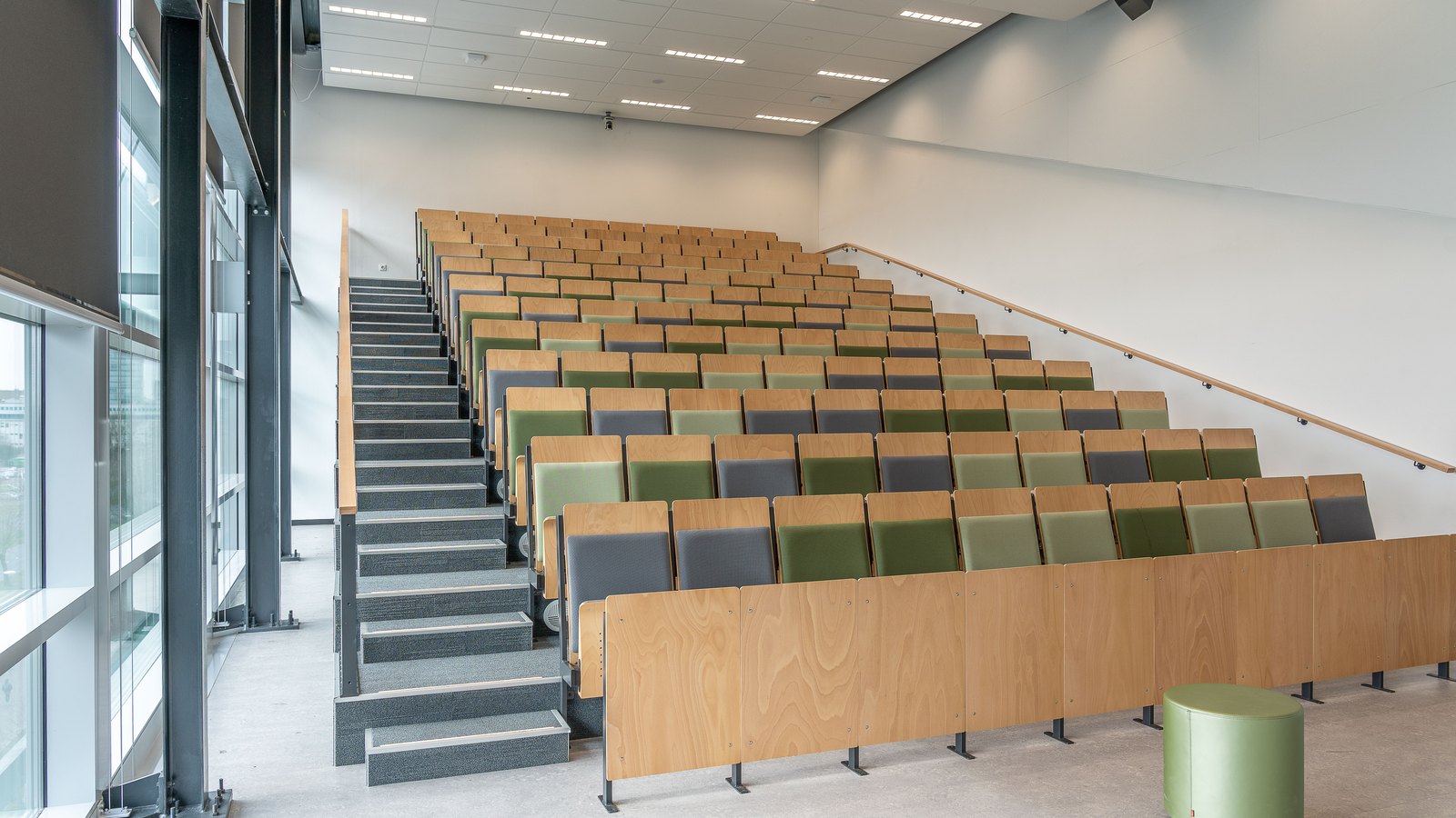 An empty modern university lecture hall with tiered wooden seats, not a photograph of this event.