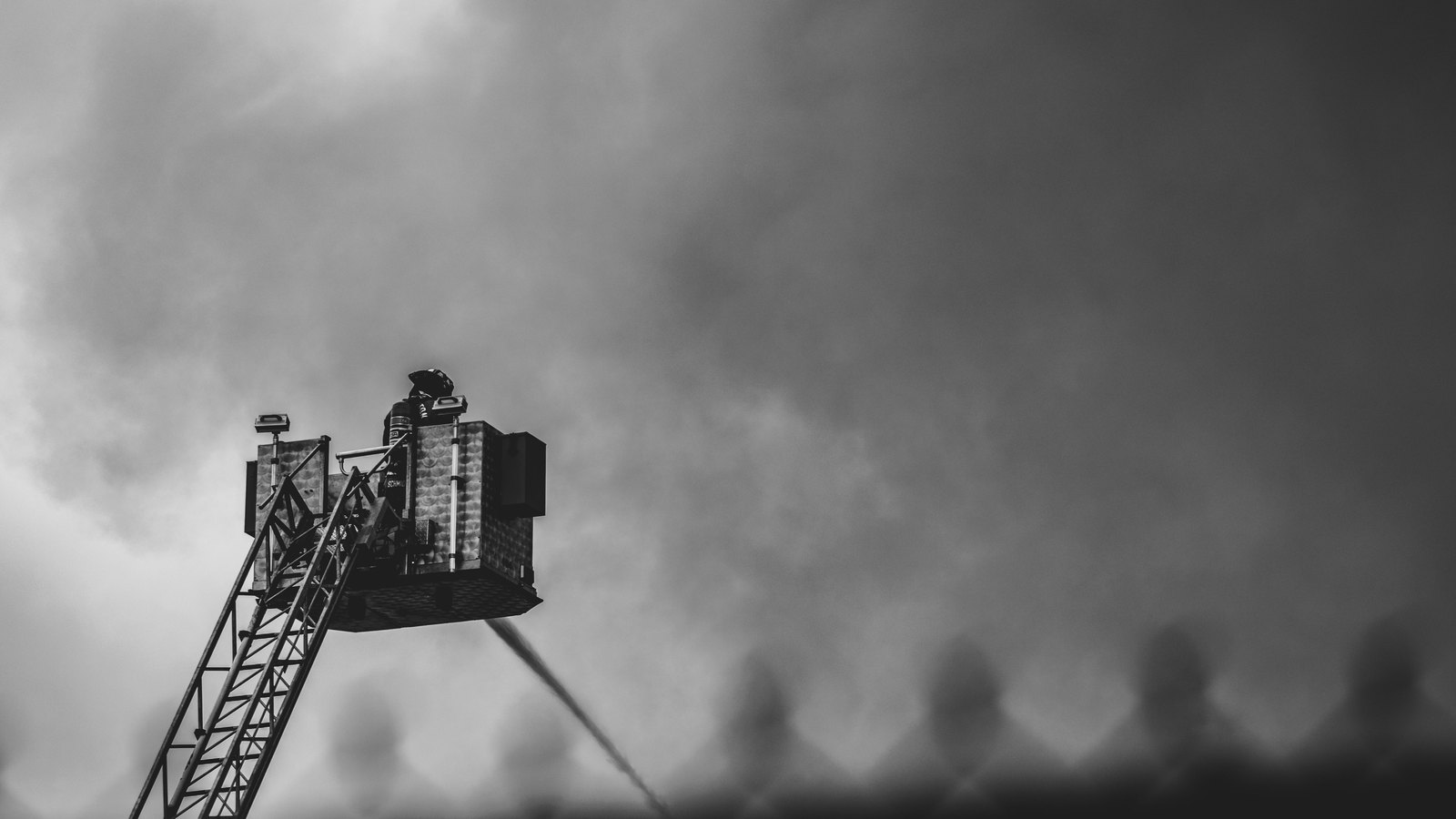 A firefighter on an aerial ladder sprays water into heavy smoke, not a photograph of this event.