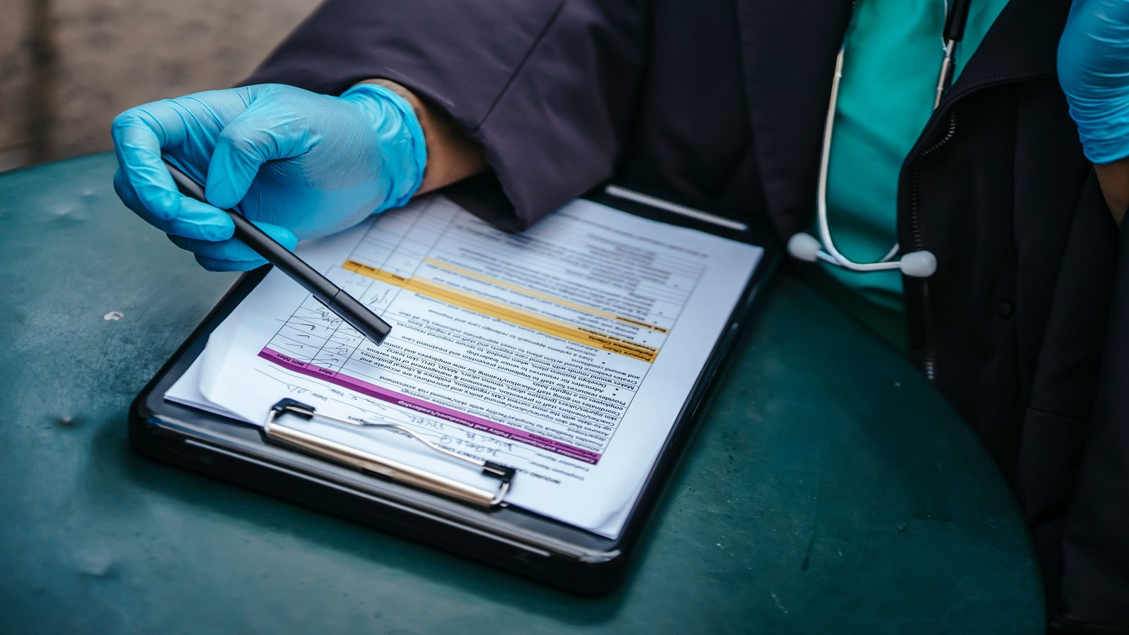 A health care worker reviews a form on a clipboard.