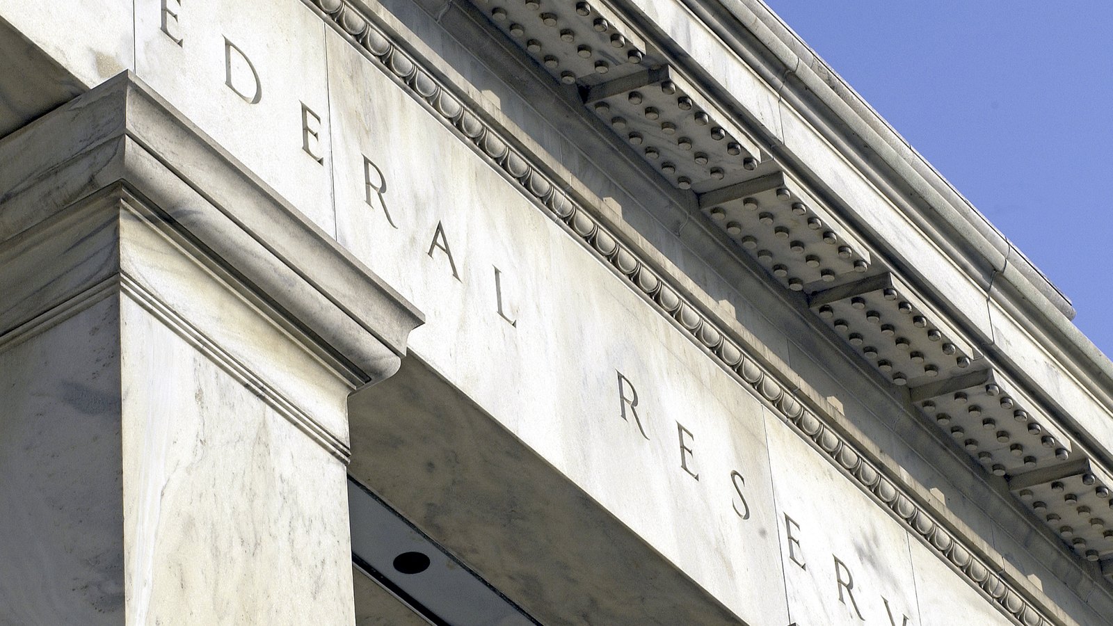 A close view of the white marble Federal Reserve Board Building shows part of the carved Federal Reserve name across its entablature.