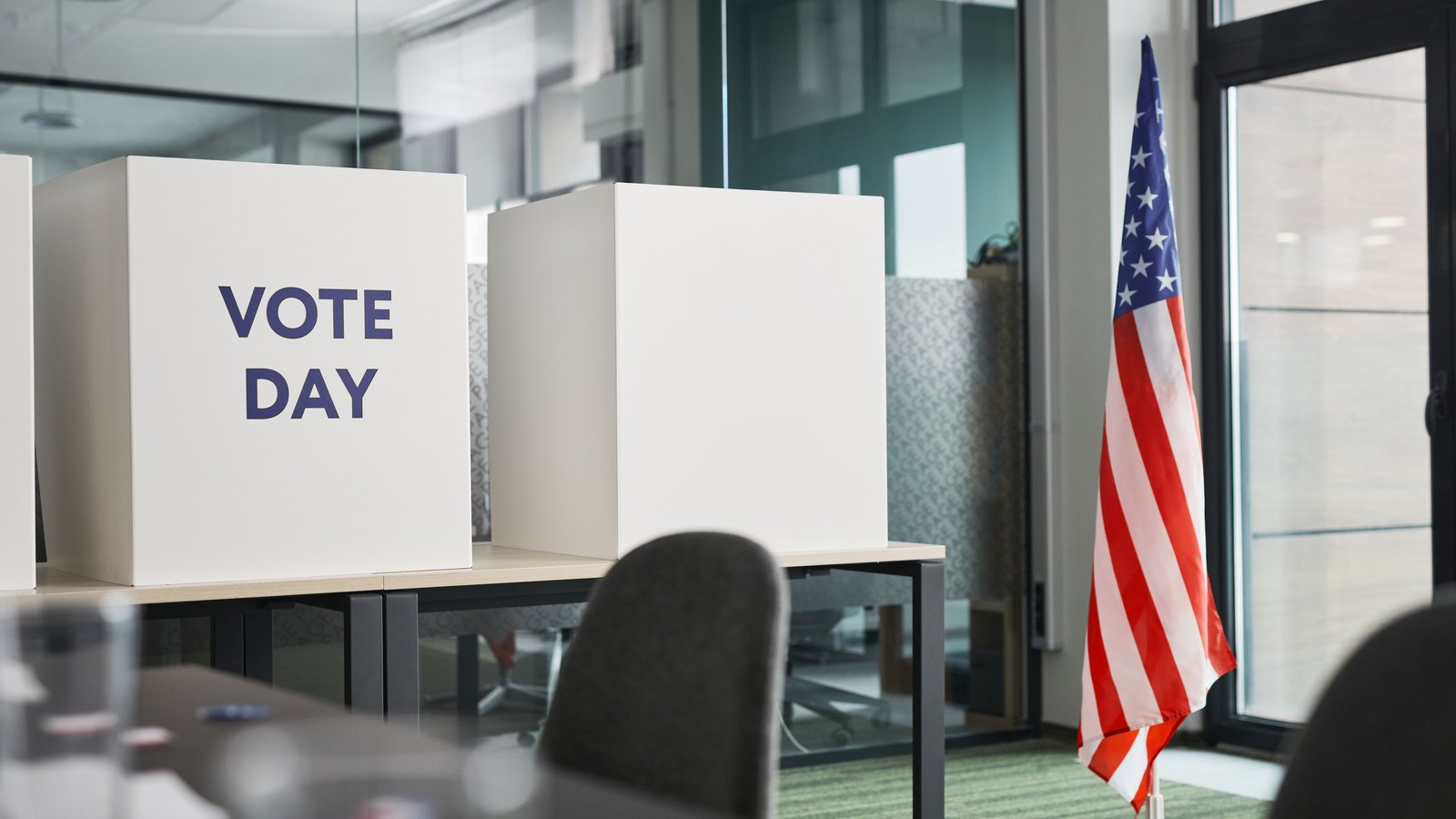 Empty voting booths beside an American flag in a generic polling-place photograph, not a photograph of this referendum.