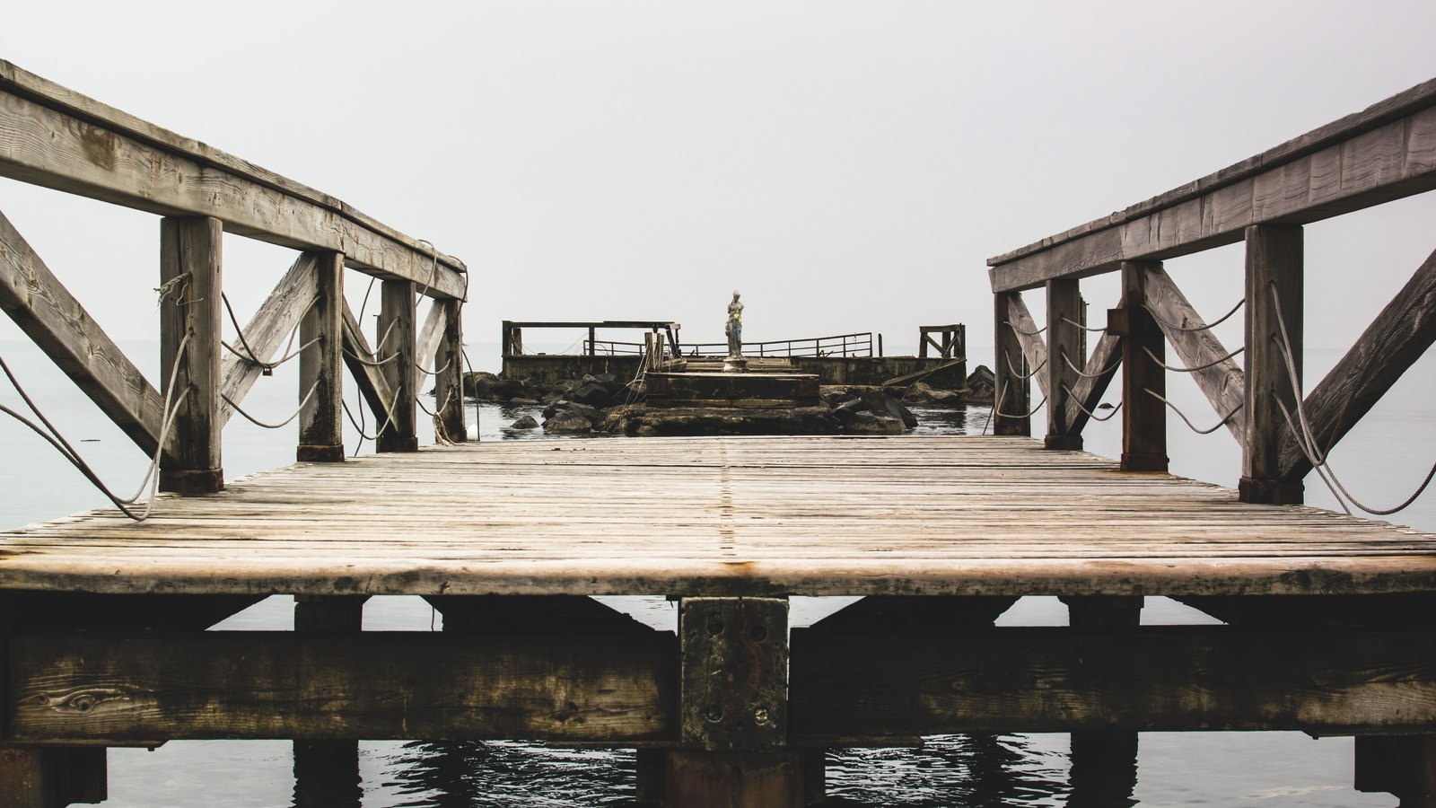 A weathered wooden pier extends over calm water, not a photograph of the Fort Myers Beach project.