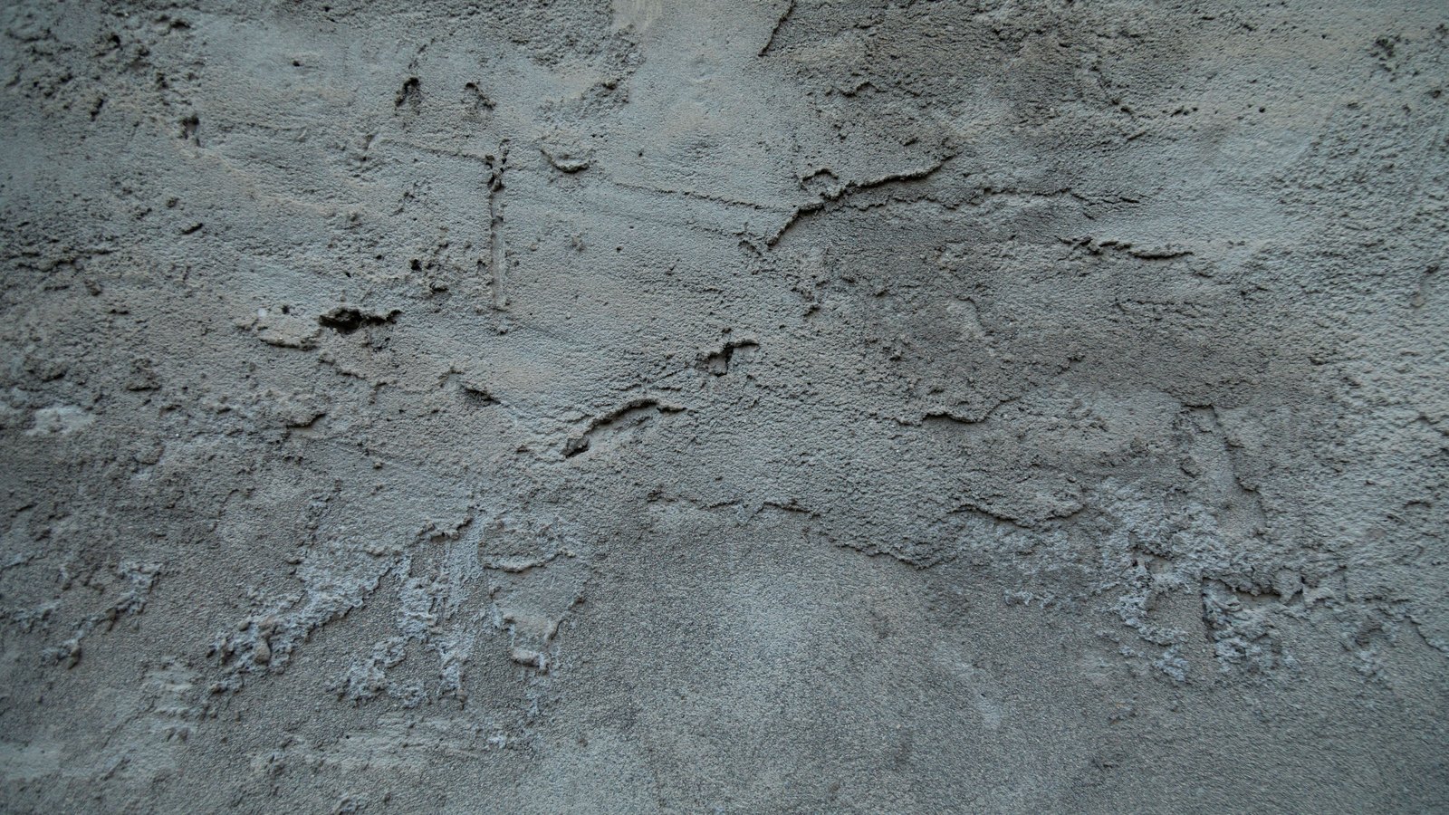 A close crop of a weathered grey cement surface, the render pitted and flaking in shallow horizontal bands across the whole frame, with no text, marking or object in view.