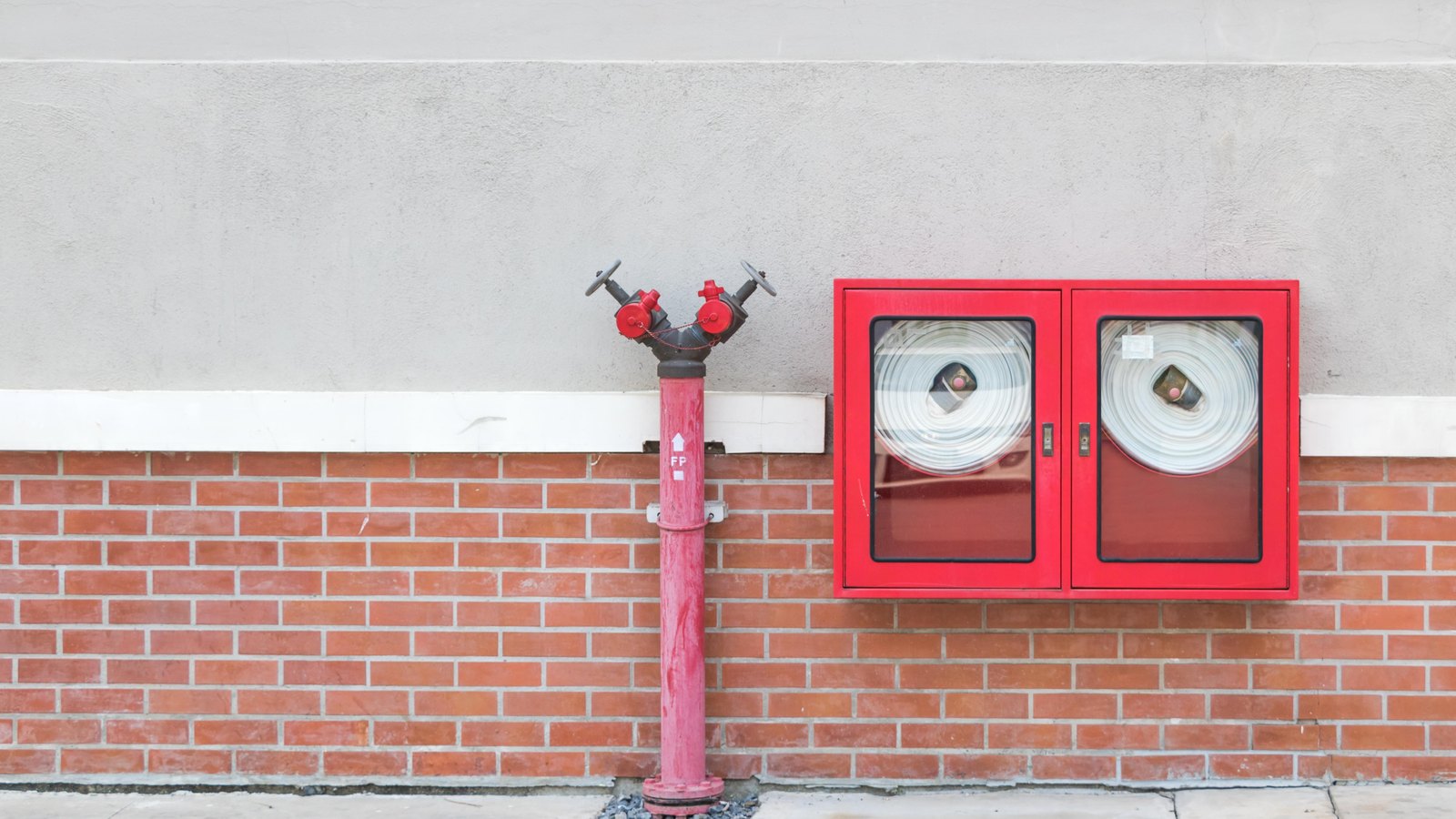 Coiled fire hoses in a red cabinet beside a standpipe, not a photograph of this event.