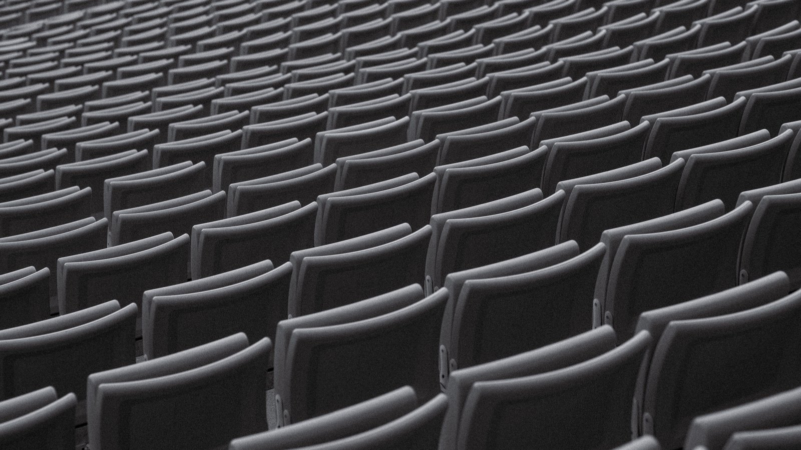 Rows of empty gray seats in an auditorium, not a photograph of this event.