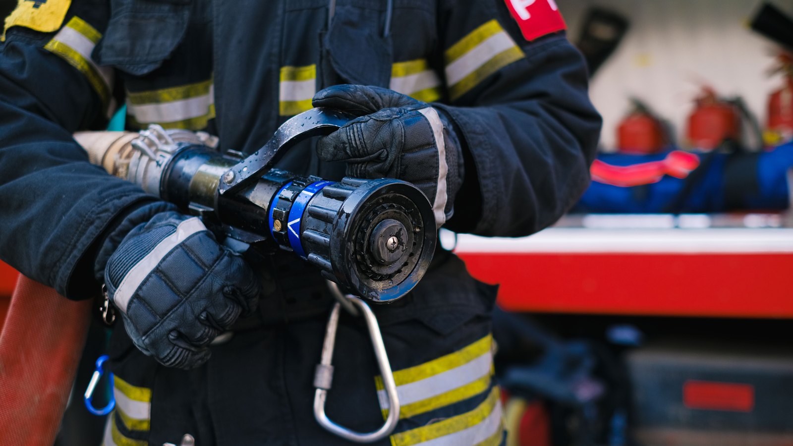 A firefighter's gloved hands holding a hose nozzle, not a photograph of this event.