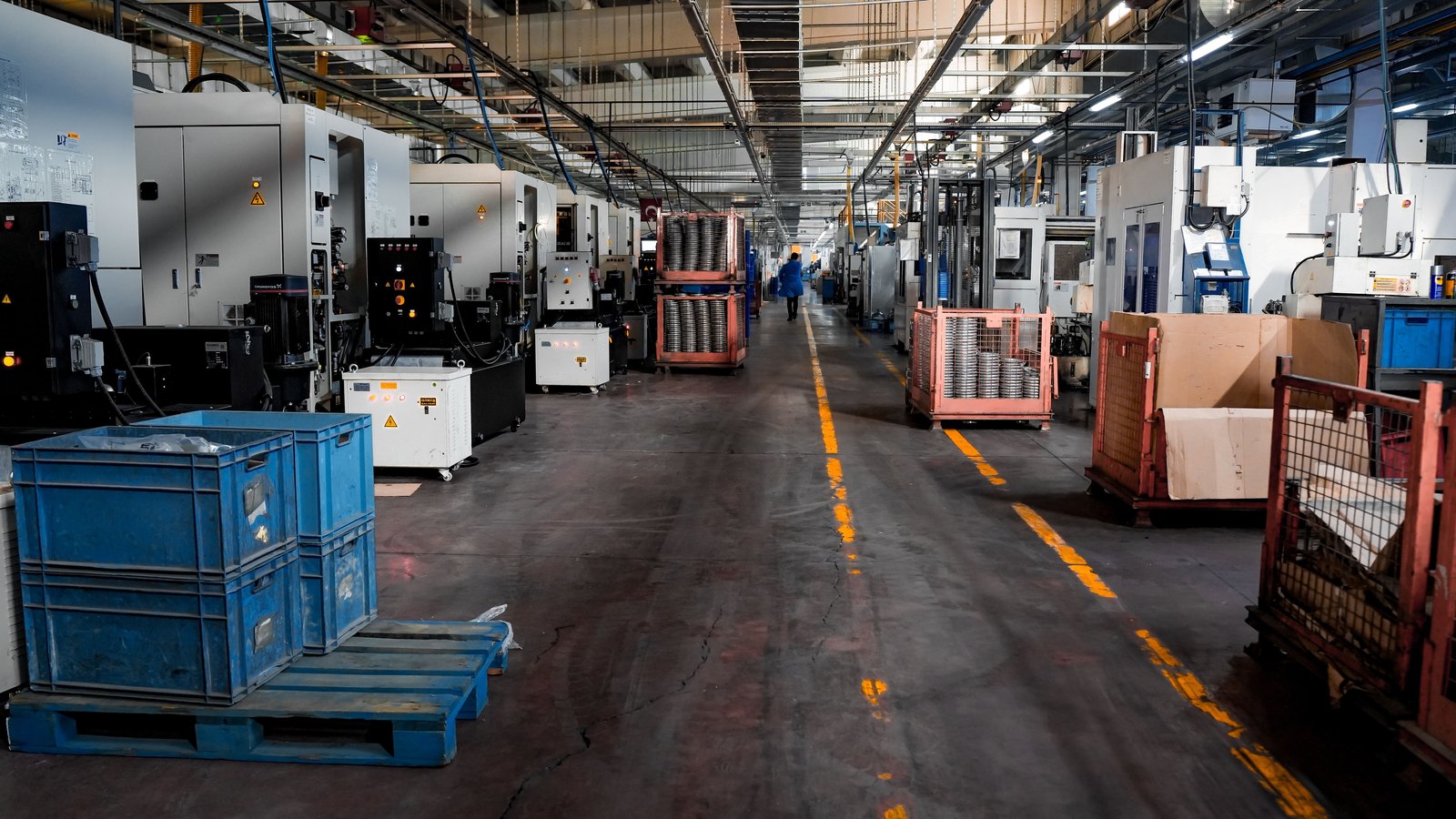 Machining stations, parts bins and carts line a working factory floor