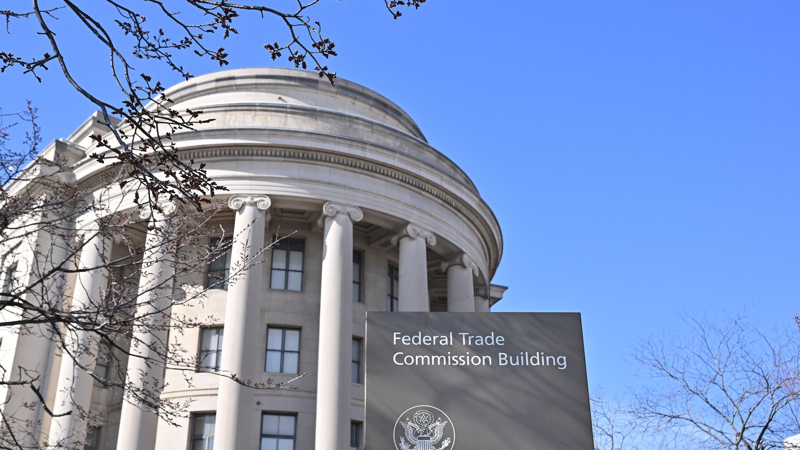 The curved front of the Federal Trade Commission Building stands behind an agency sign