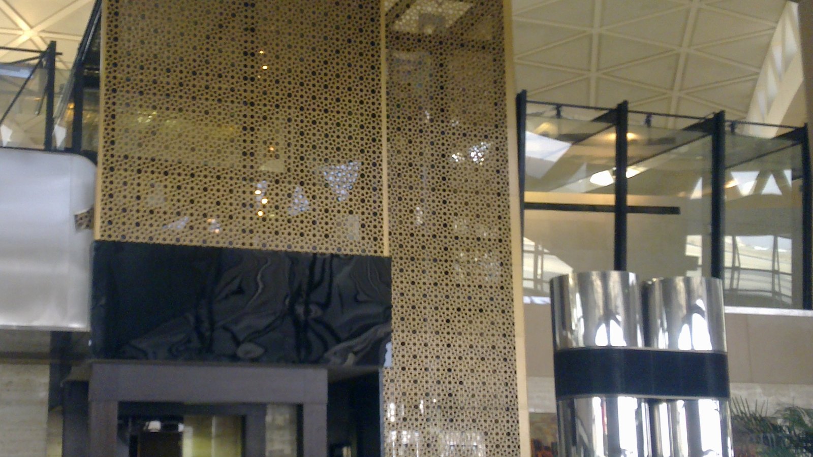 A patterned architectural screen and revolving door inside King Khalid International Airport in Riyadh.