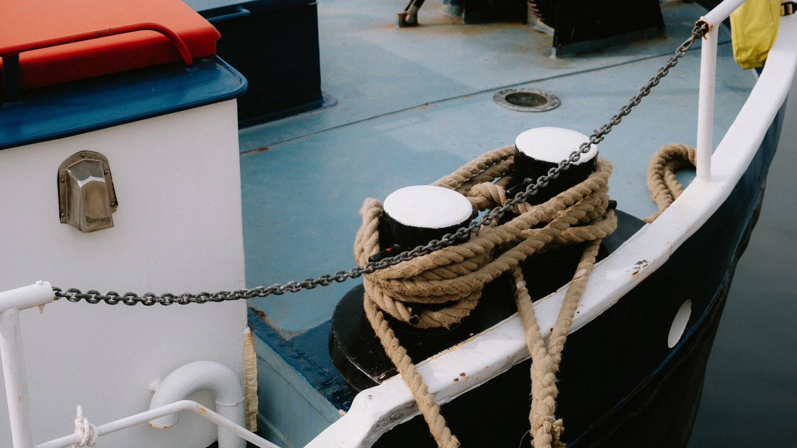 Thick mooring ropes coiled around two bollards on a working vessel deck