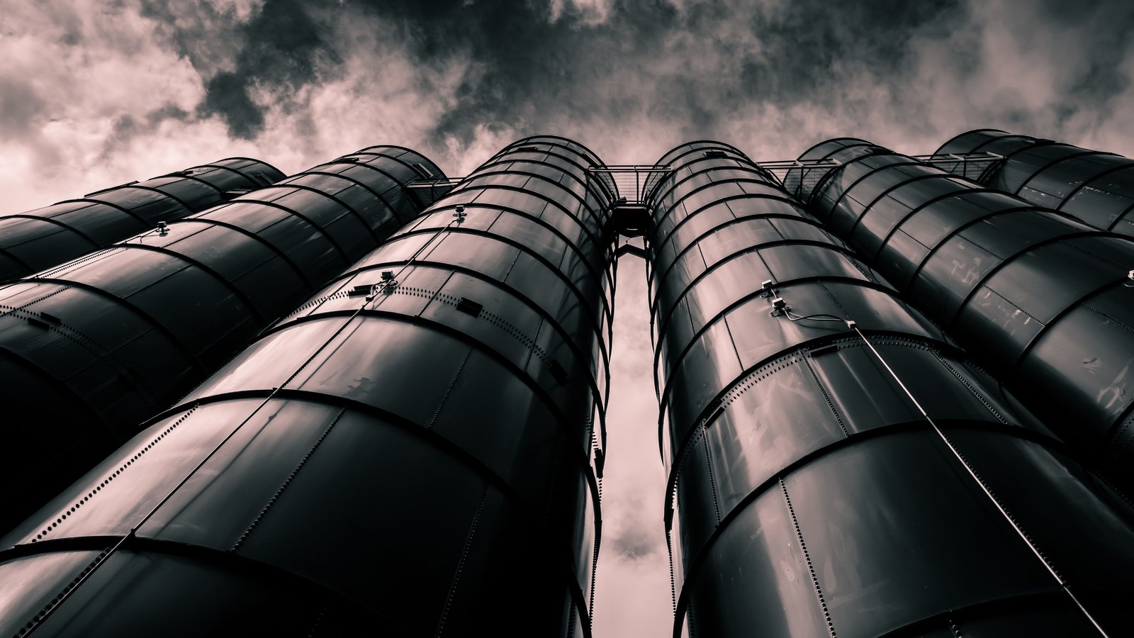 Industrial storage silos rise beneath dark clouds.