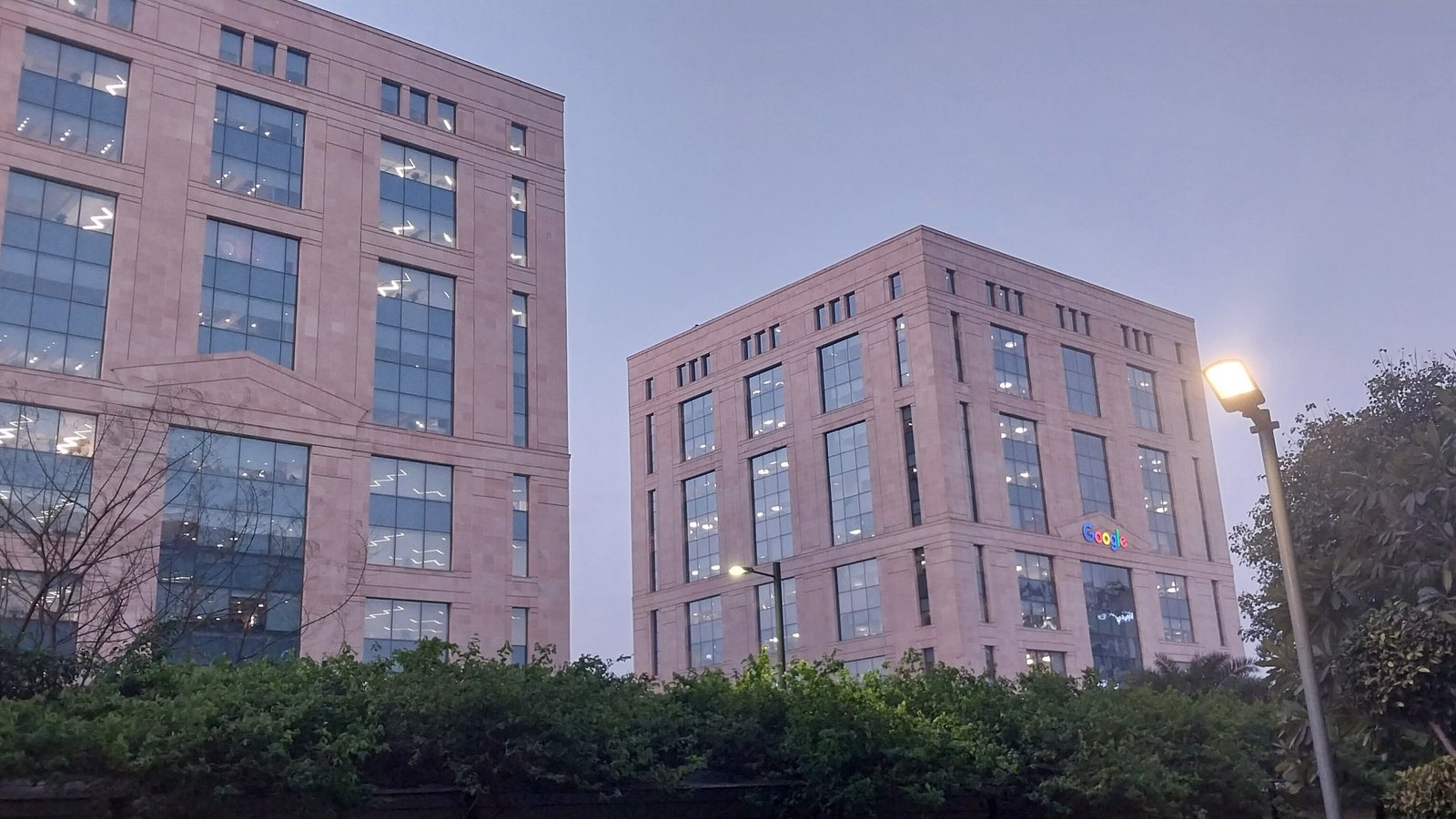 Two stone office towers in Gurgaon, India, with a Google sign on one building.
