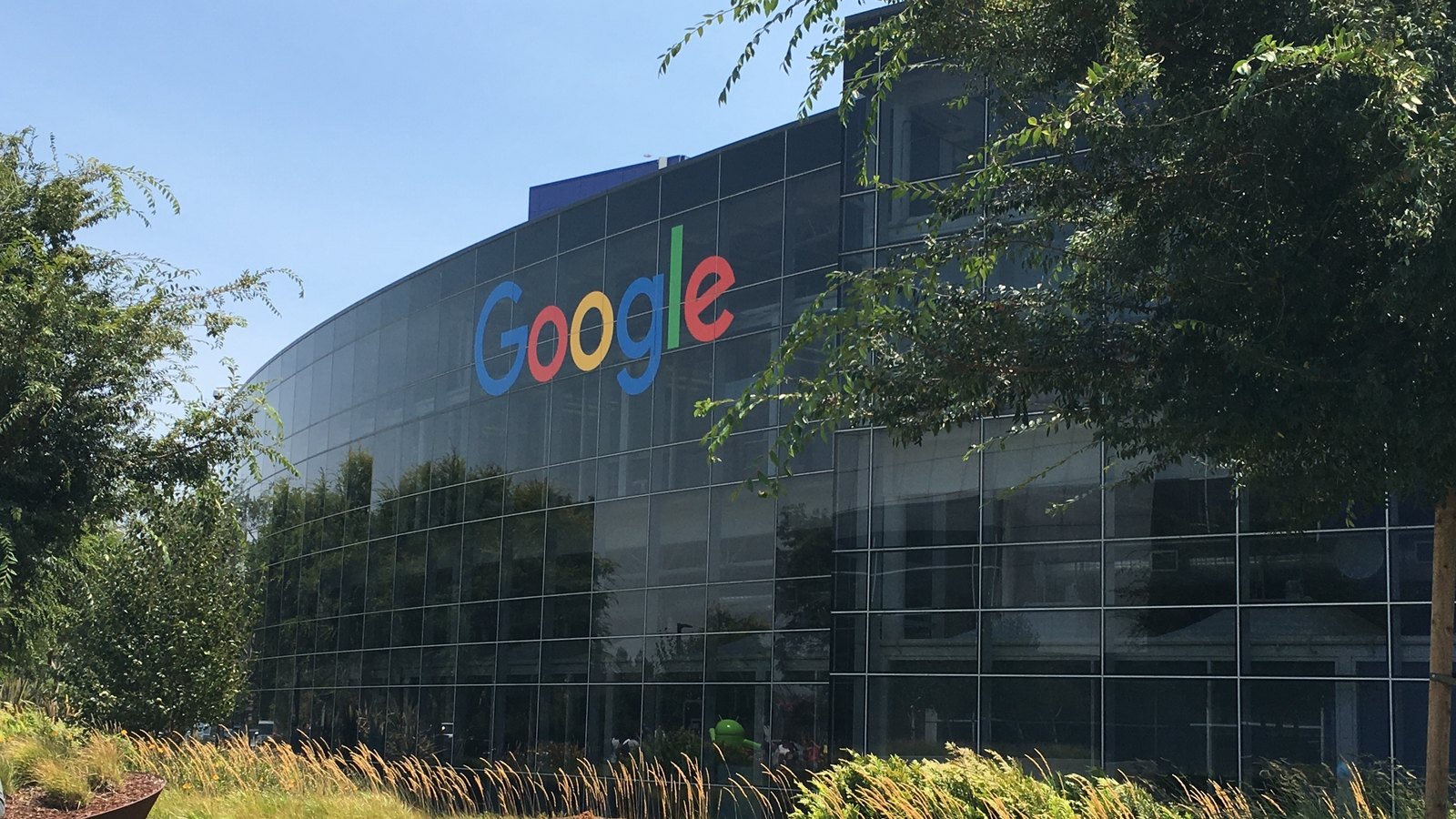 The Google logo is mounted on the glass facade of a Googleplex office building in Mountain View, California.