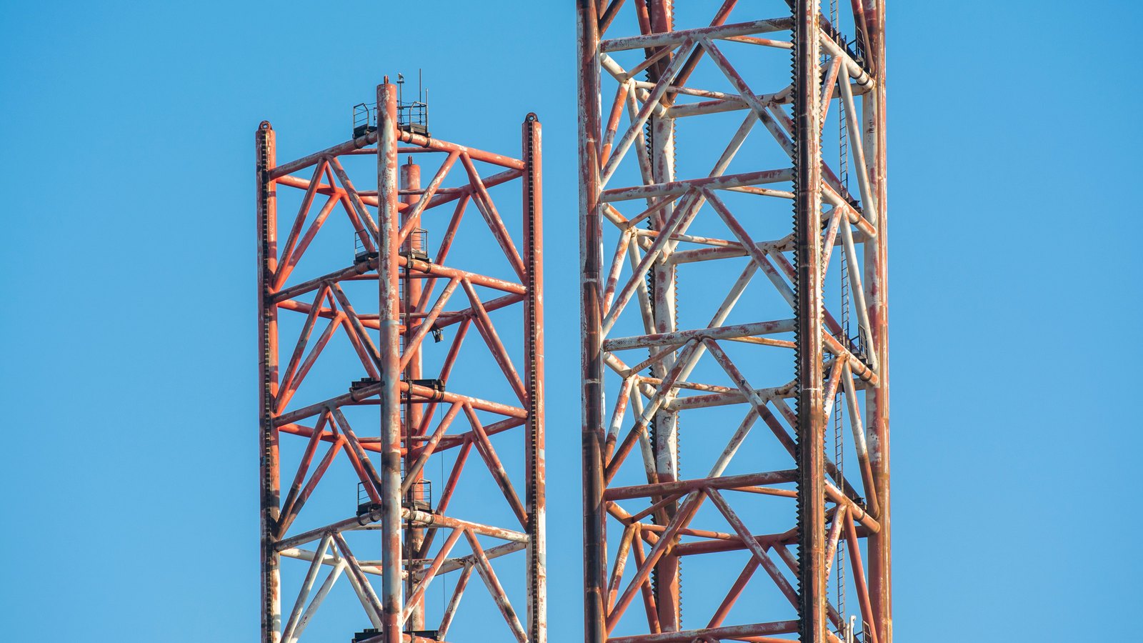 Two construction crane towers against a clear blue sky, not a photograph of this project.