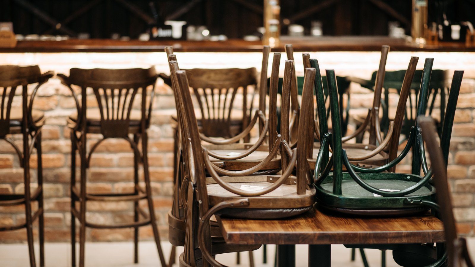Wooden restaurant chairs stacked upside down on empty tables, not a photograph of this event.