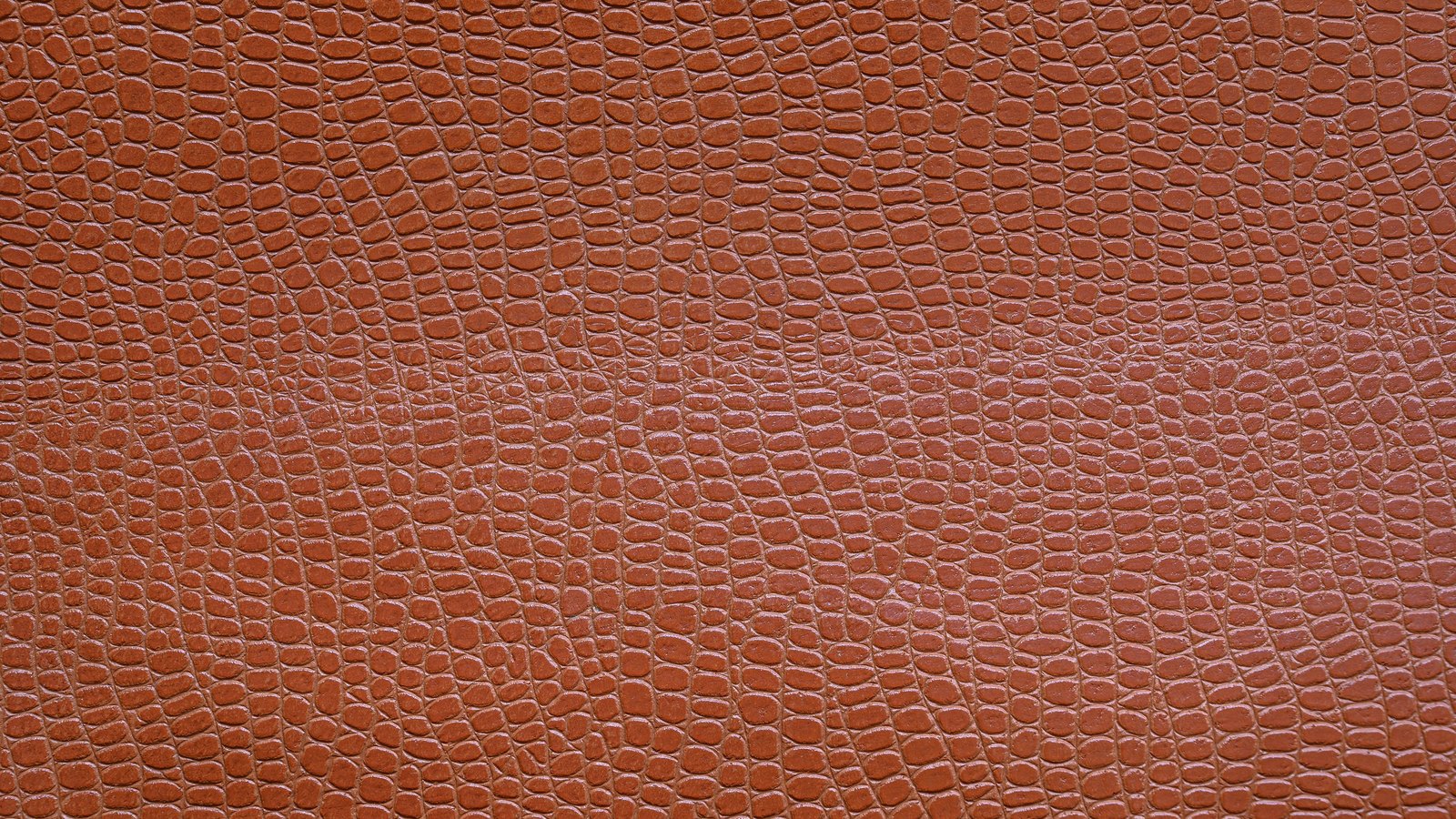 Close macro of reddish brown embossed leather filling the frame, pebbled grain with no markings or lettering.