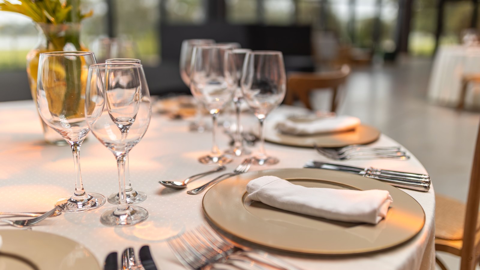 Wine glasses and folded white napkins are arranged across a set restaurant table.