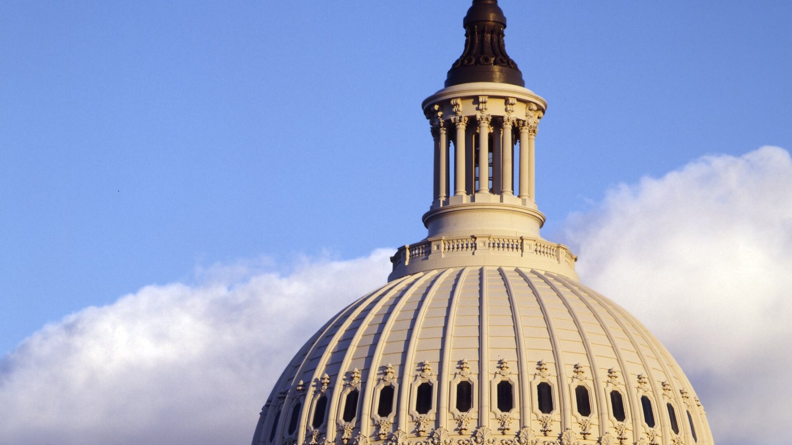 The United States Capitol dome in Washington, lit by late-day sun beneath a blue sky.