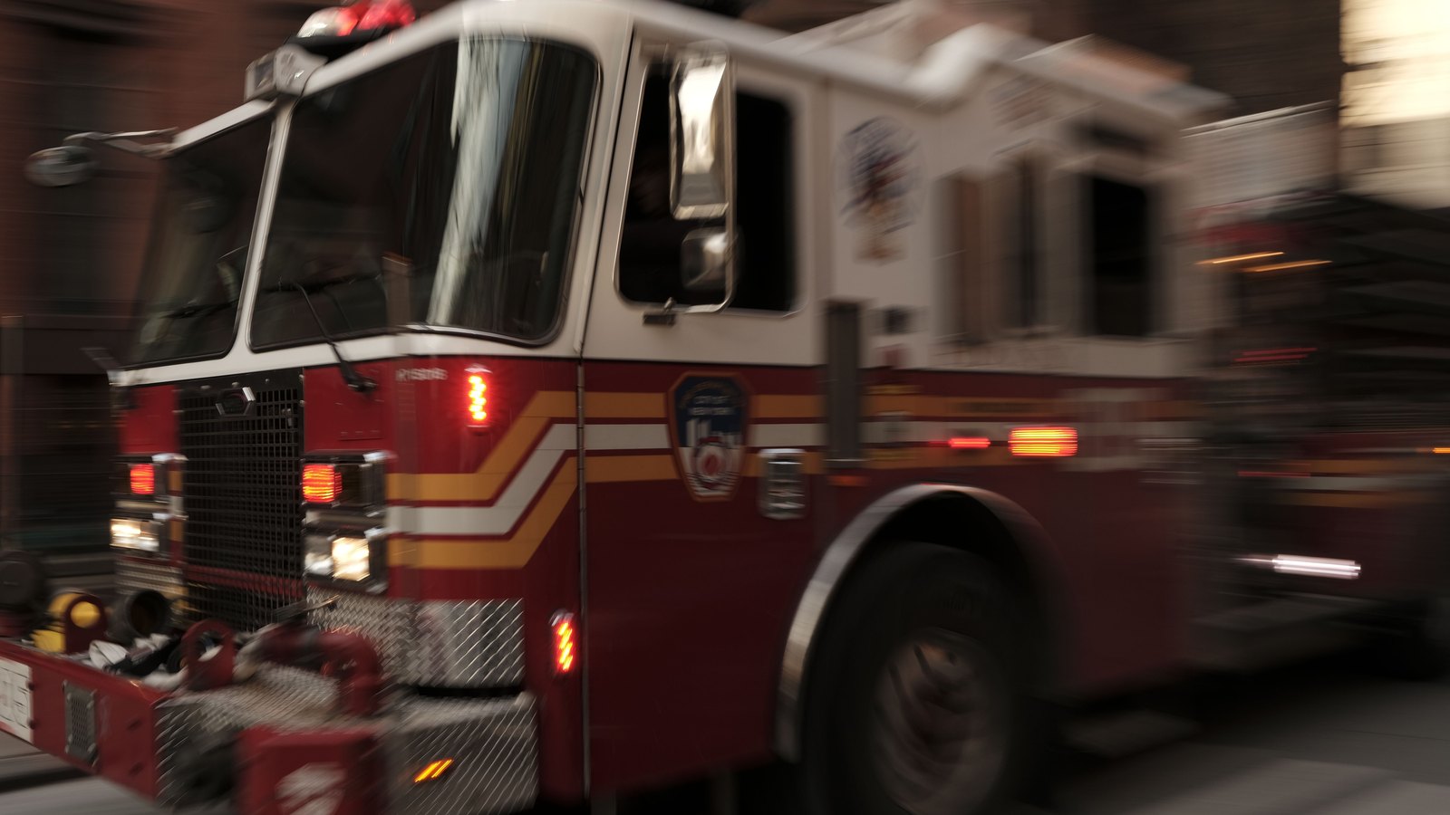 A fire engine with emergency lights moving through a city street, not a photograph of this event.