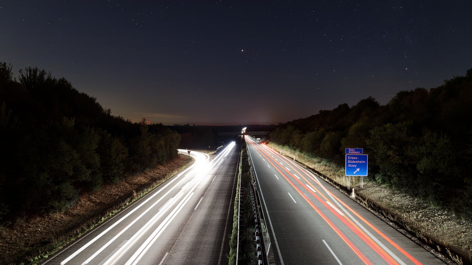 An illuminated highway at night with light trails.