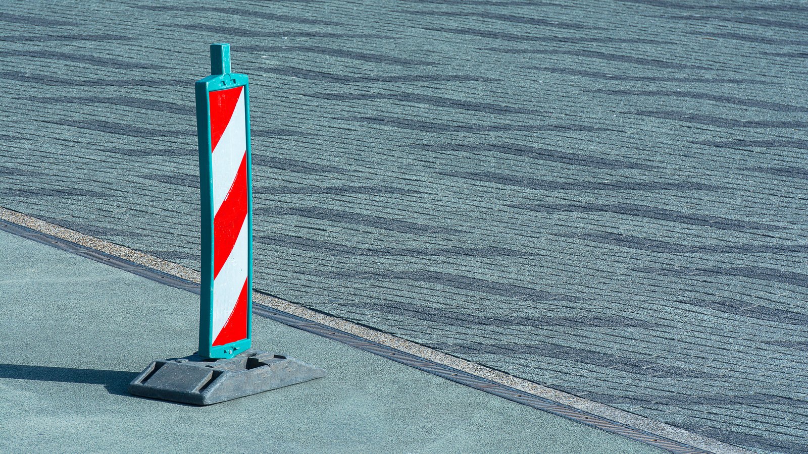 A red-and-white striped temporary traffic marker stands on pavement, not a photograph of this event.