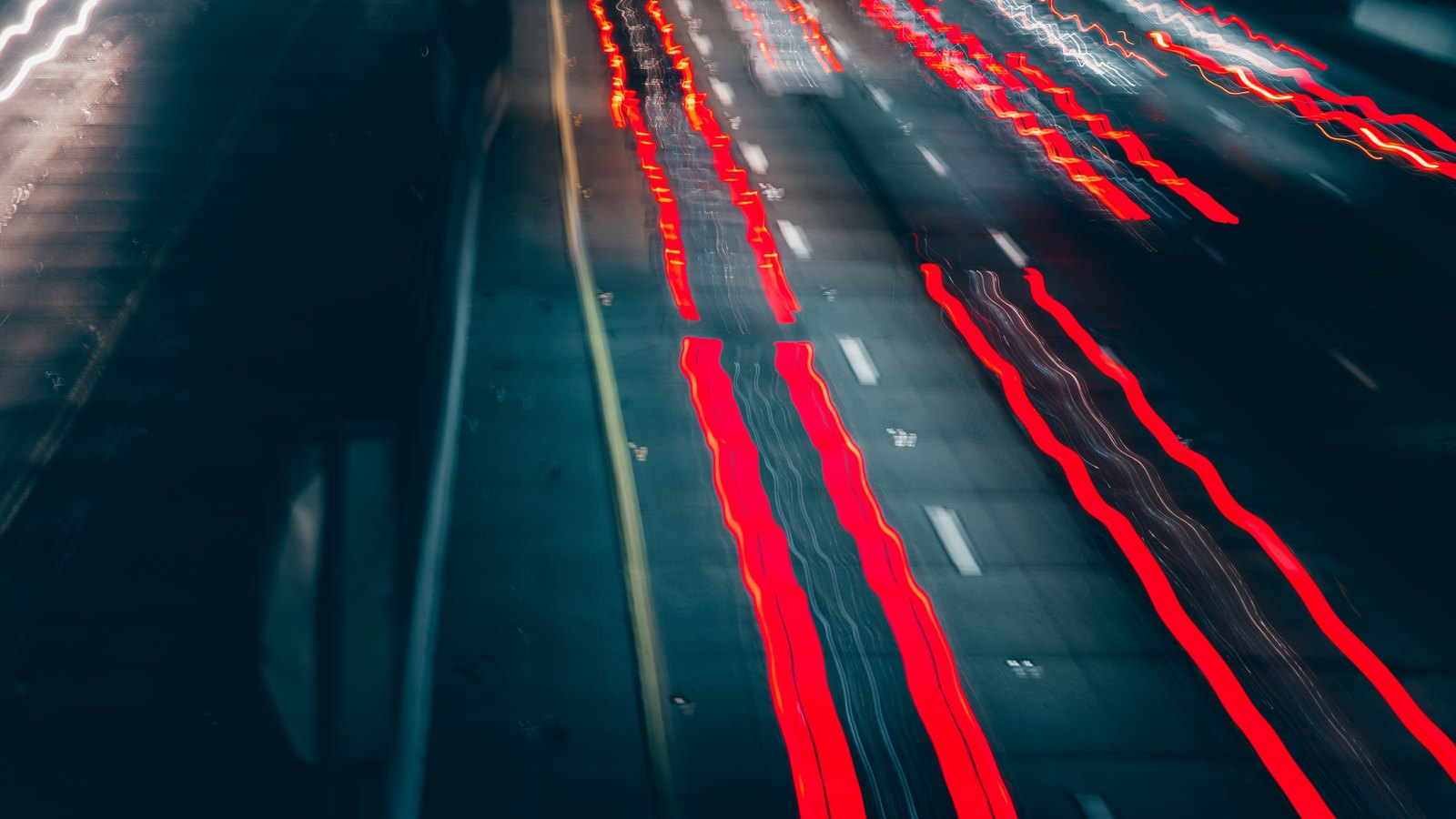 Red vehicle light trails cross a multilane highway at night, not a photograph of this event.