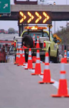 Orange cones channel traffic toward an incident-response truck with an arrow board, not a photograph of this event.