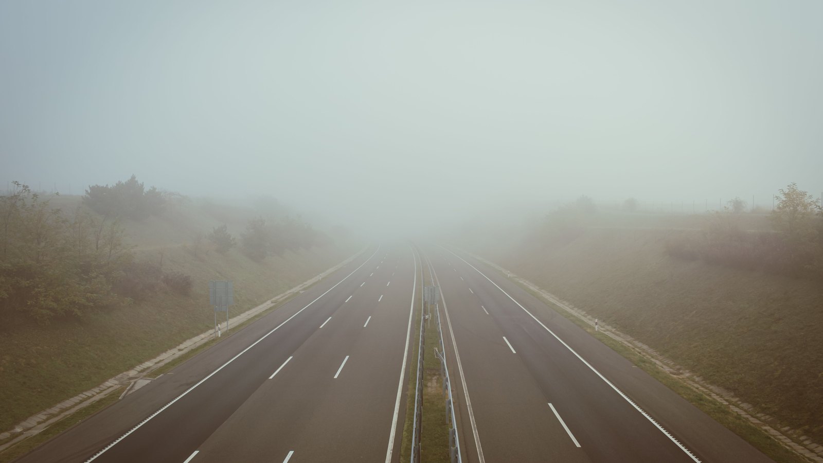 An empty divided highway disappearing into dense fog, not a photograph of this event.