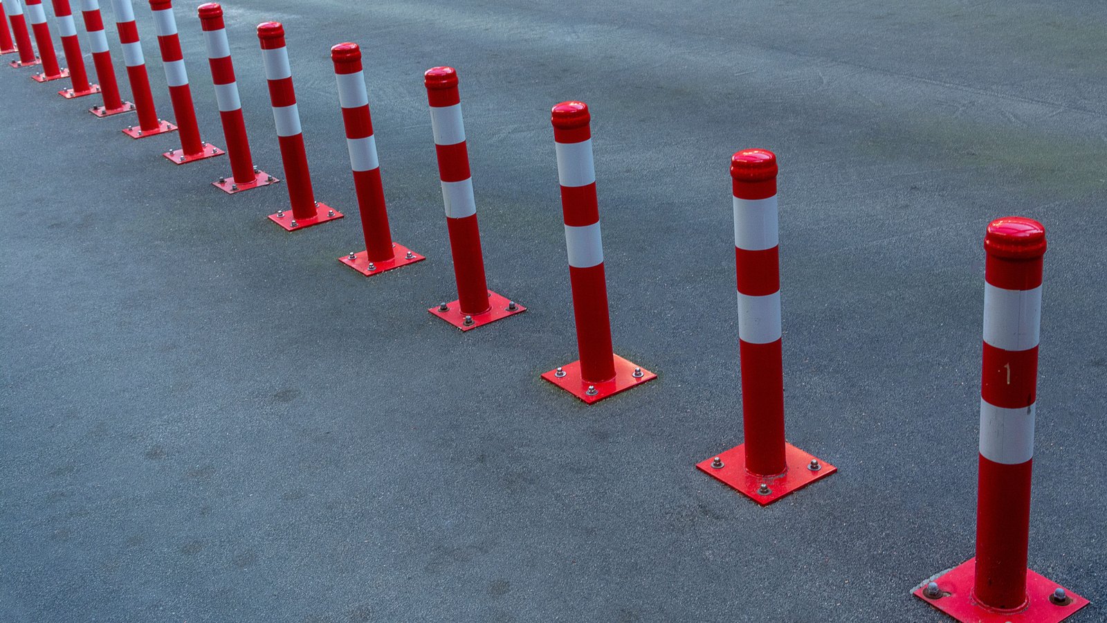 A line of red and white flexible traffic posts separates a lane on an asphalt road, not a photograph of this event.