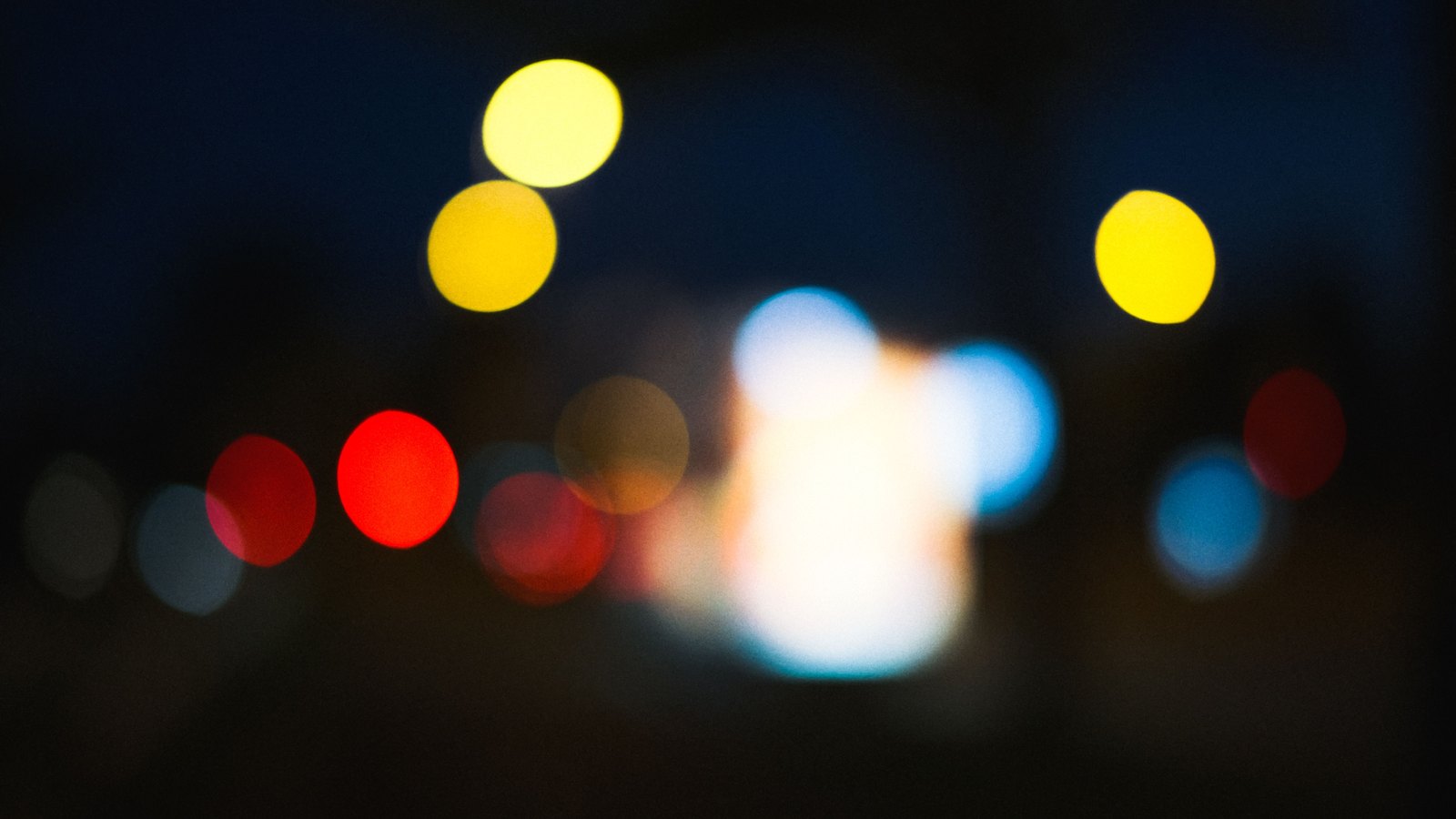 Out-of-focus red, blue and amber lights glow against a dark background, used as a general illustration and not a photograph of this event.