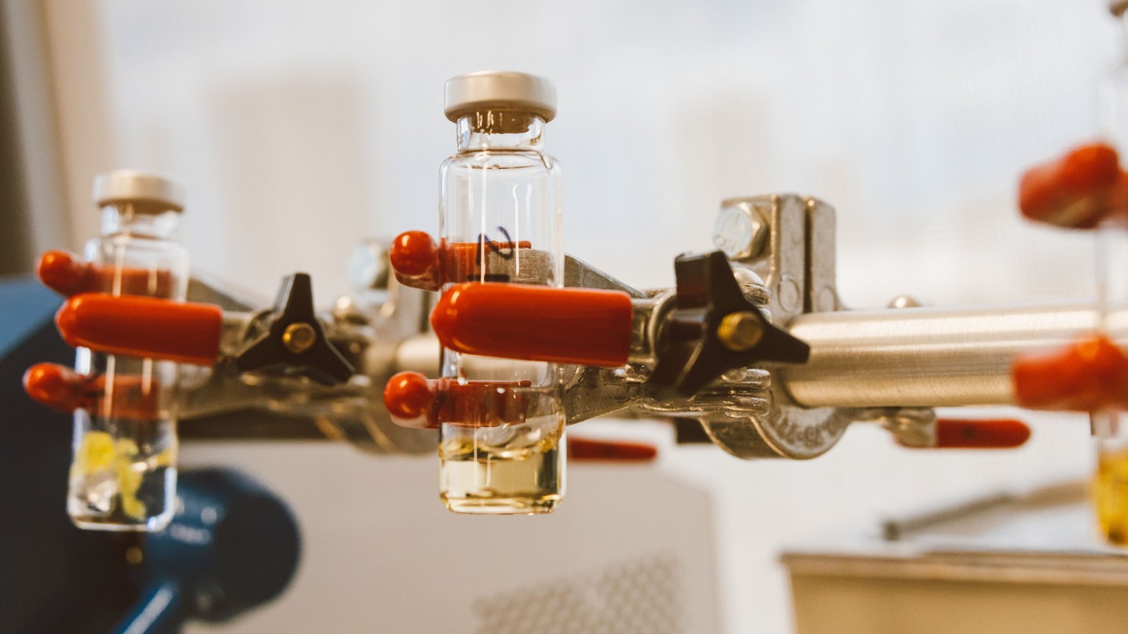Clear laboratory vials held in metal clamps.