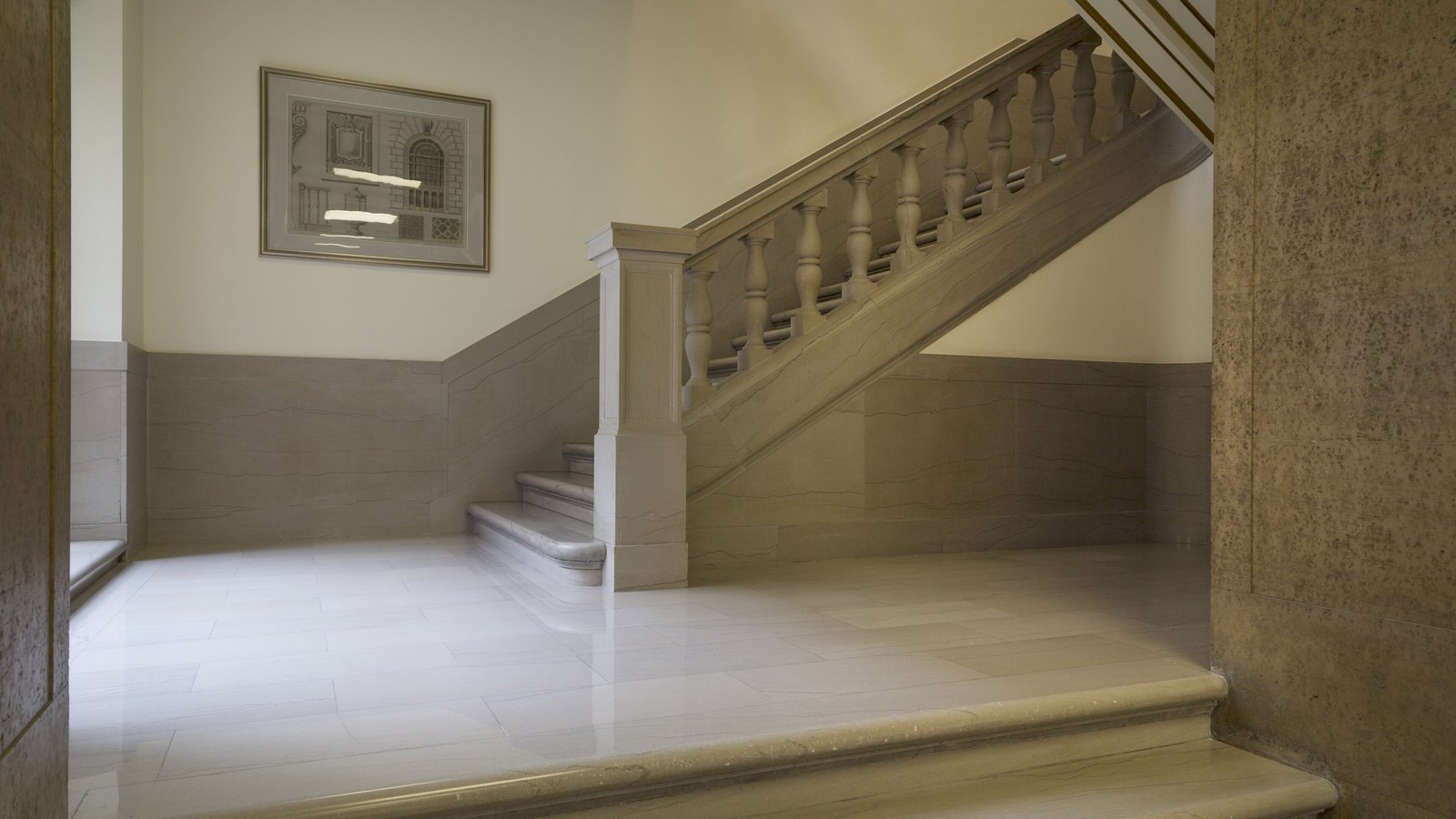 A pale marble staircase inside the Internal Revenue Service Building in Washington, with a stone balustrade and a framed architectural drawing on the wall.