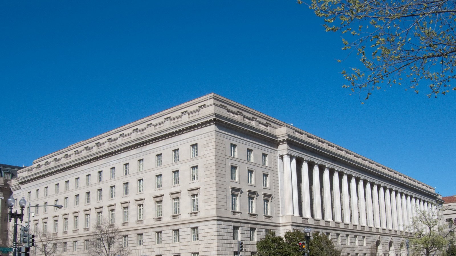 The Internal Revenue Service Building at 1111 Constitution Avenue in Washington, seen from the 12th Street corner on a clear day. The limestone facade runs to a long Ionic colonnade along Constitution Avenue. No person, vehicle or sign is in the frame.