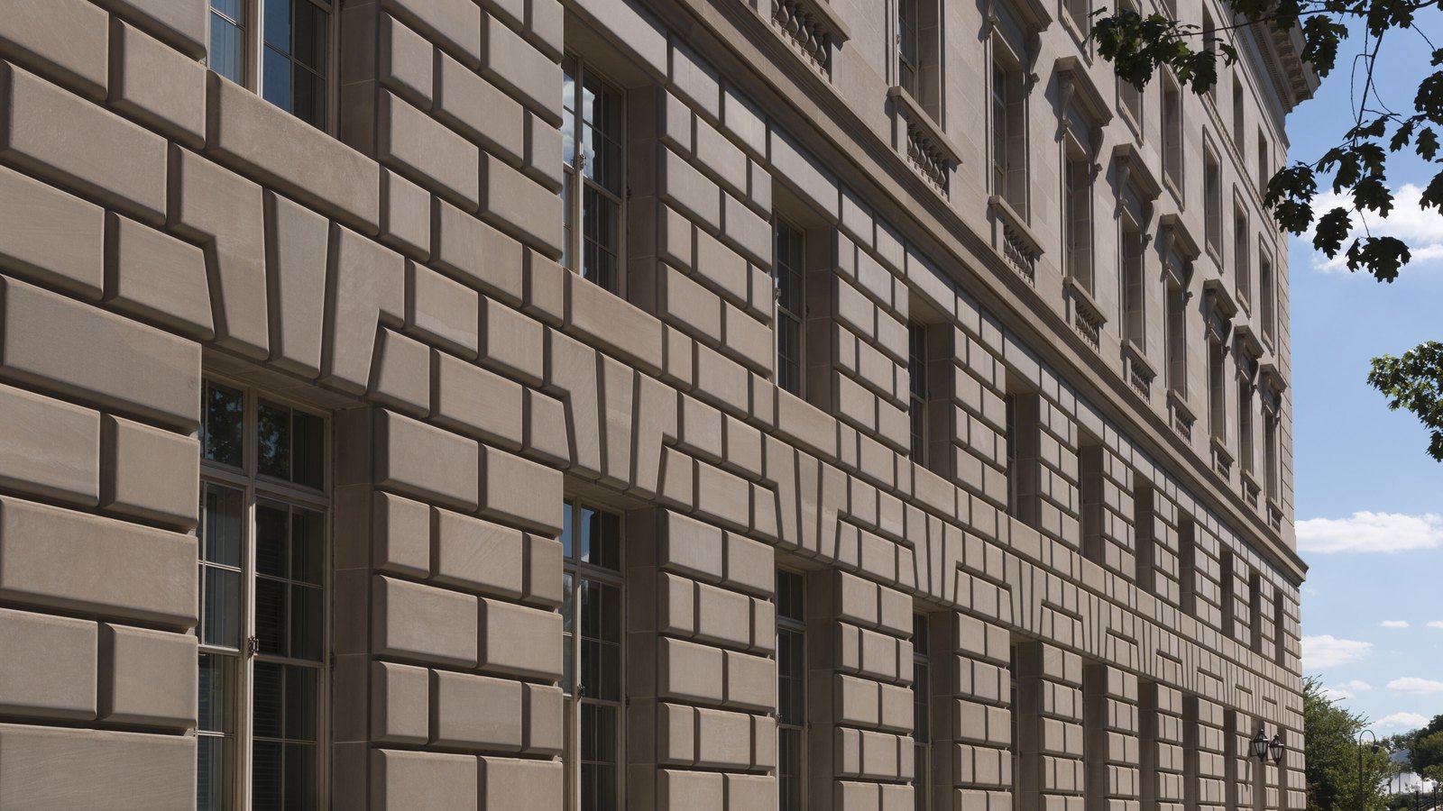 The limestone side wall of the Internal Revenue Service Building in Washington recedes beside an empty path.