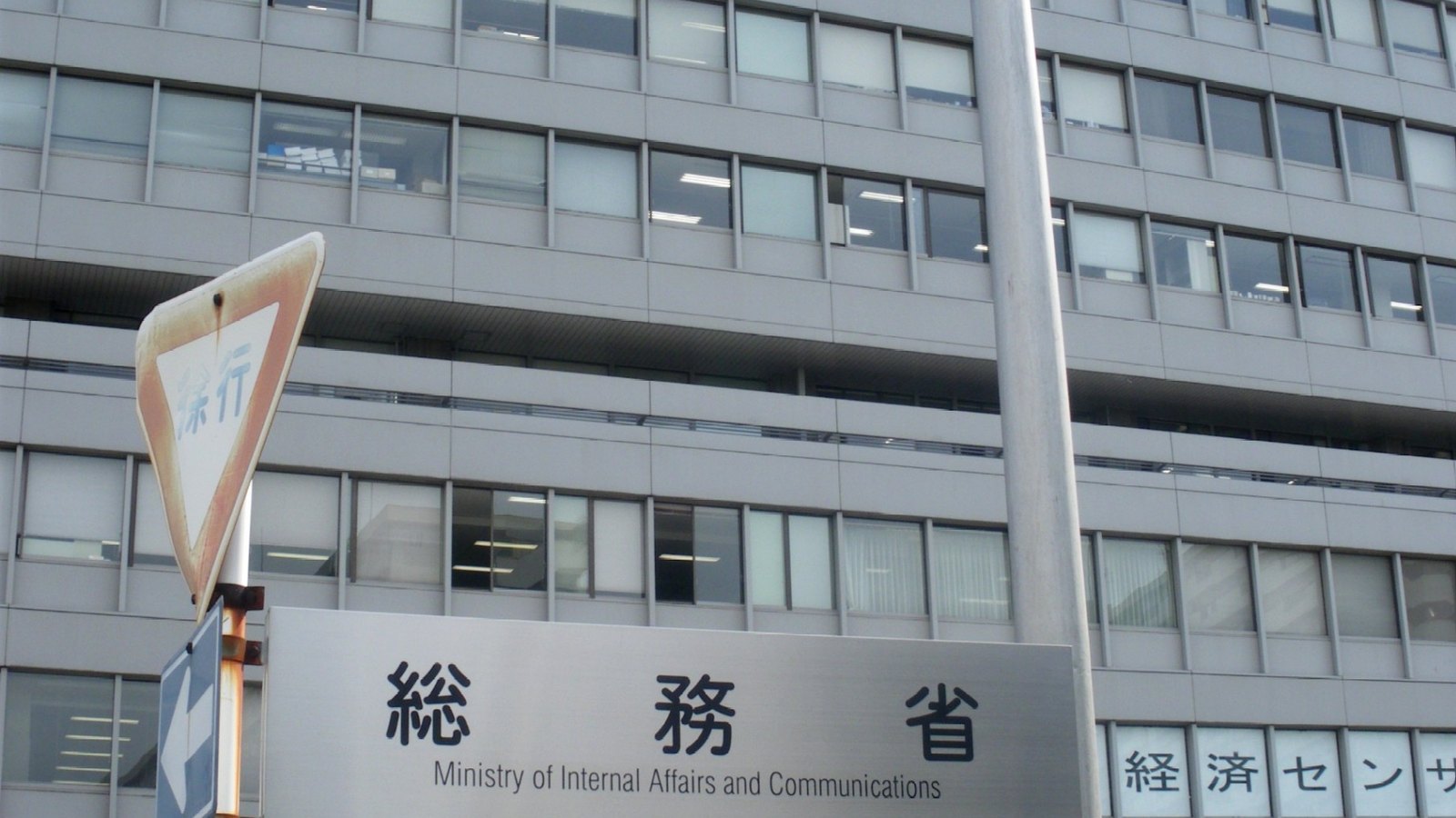 The Statistics Bureau of Japan office building in Tokyo behind the agency's Japanese and English entrance sign.