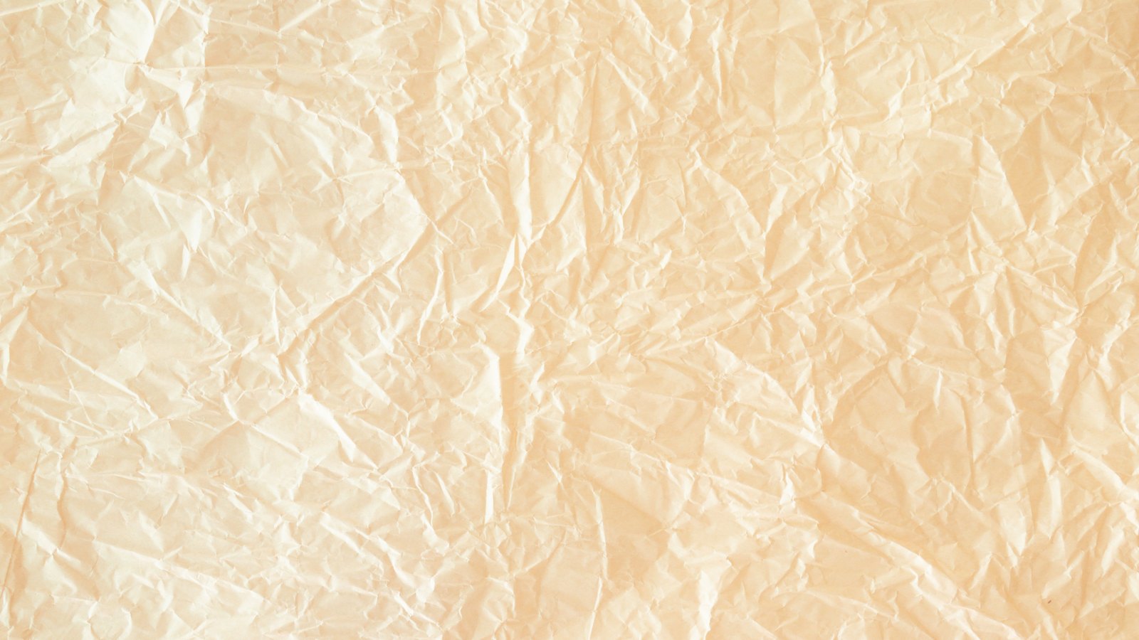 A sheet of pale cream paper filling the whole frame, its surface covered in soft irregular creases and fold lines that catch the light as fine pale ridges with shallow shadows between them. The tone shifts from near white at the left to a warmer sand colour towards the right. No text, brand mark, person or place is in view.