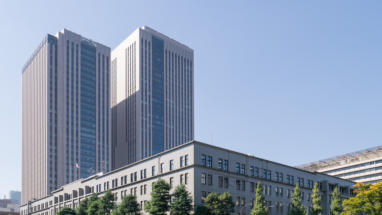 The Ministry of Finance building in Tokyo, with two office towers behind it under a clear sky.
