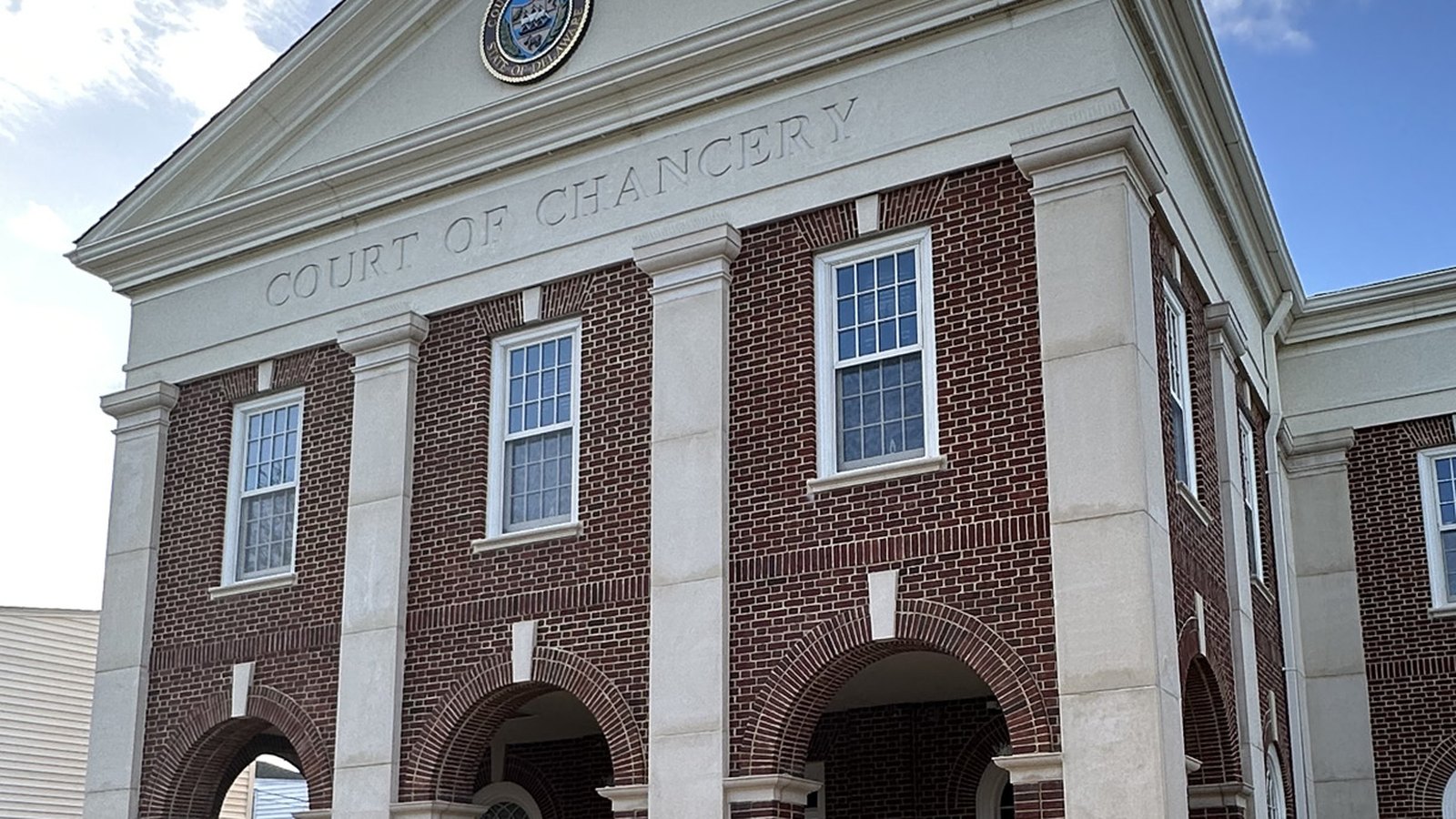 A brick and stone courthouse seen from below, with COURT OF CHANCERY carved across the pediment and the Delaware state seal set above it.