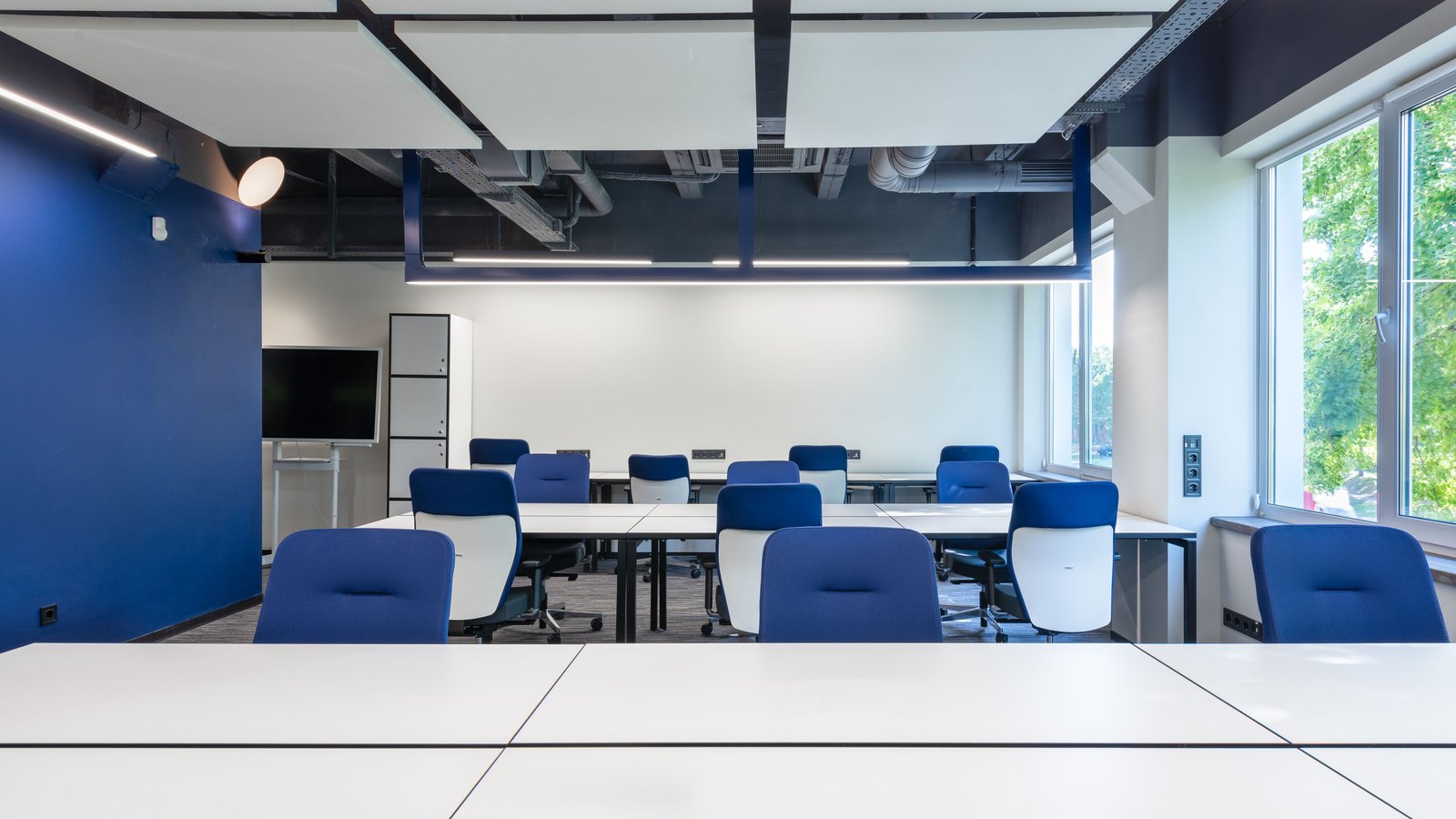 Rows of empty desks and blue chairs fill an open office.