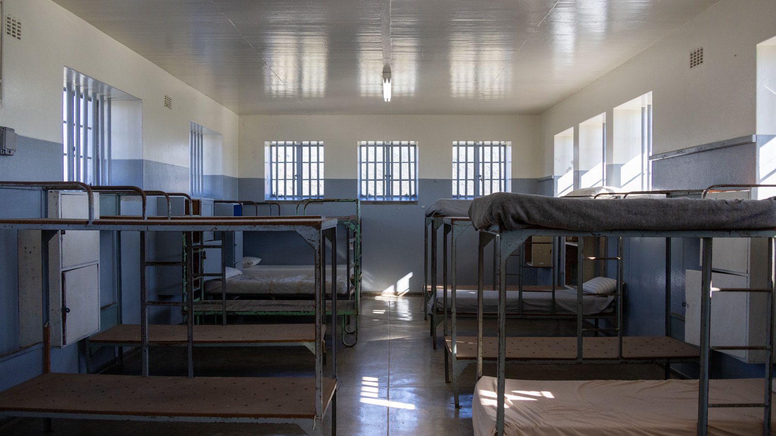 An empty institutional room with metal bunk beds and barred windows, a stock image and not a photograph of this case.