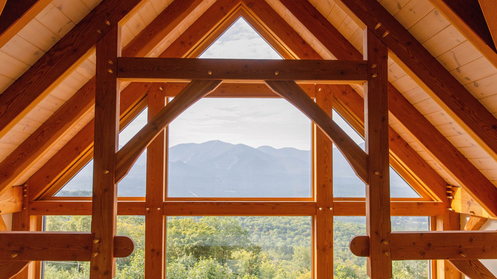 Heavy timber beams frame a house interior facing a mountain view, not a photograph of a KB Home property.