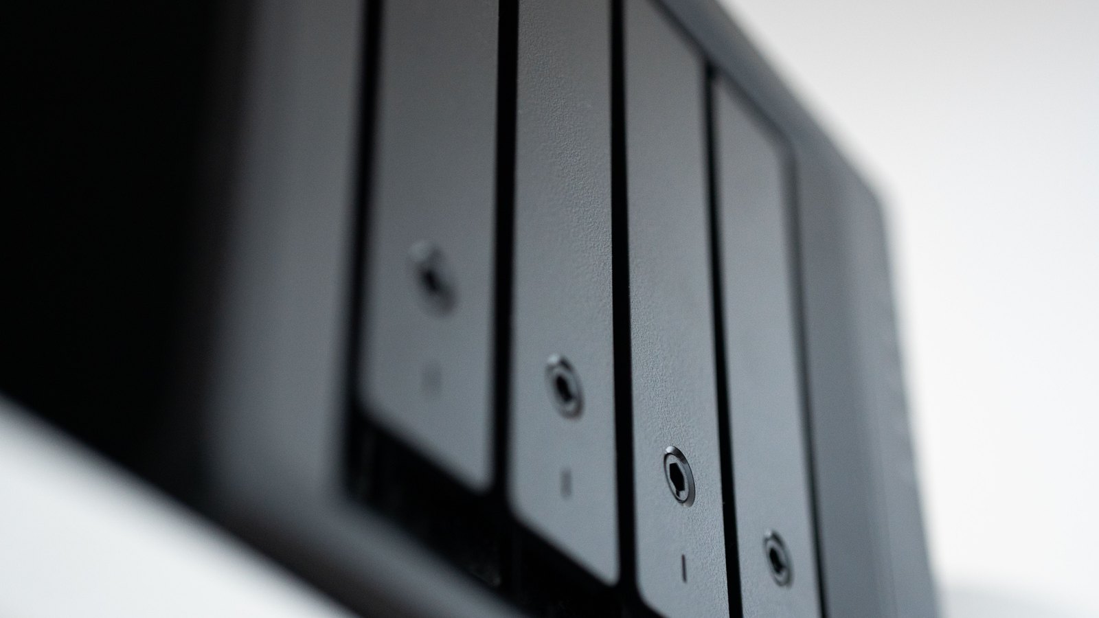 Four black drive bays in a compact data storage unit, viewed close up.